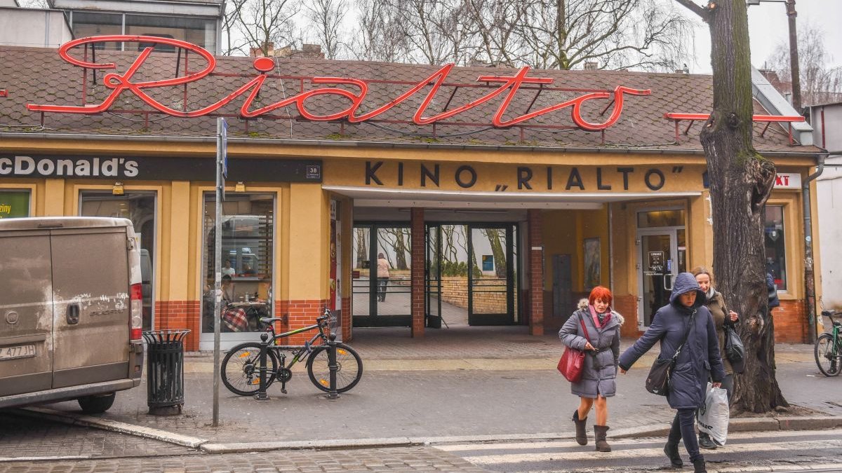 Zdjęcie przedstawia budynek z napisem "Kino Rialto". Obok widać ludzi przechodzących przez przejście dla pieszych.