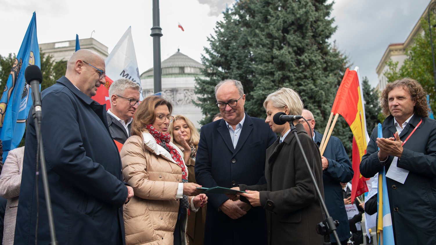 Na zdjęciu przekazanie apelu na ręce Małgorzaty Kidawy-Błońskiej, która stoi w otoczeniu samorządowców, w tle budynek Sejmu