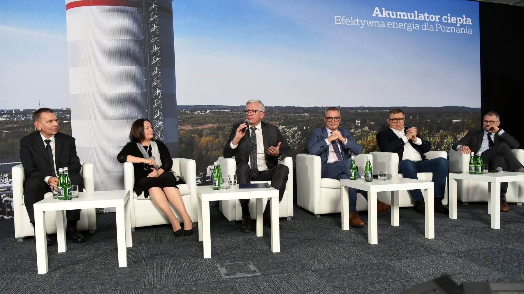 Zdjęcie przedstawia uczestników konferencji na tle zdjęcia akumulatora.