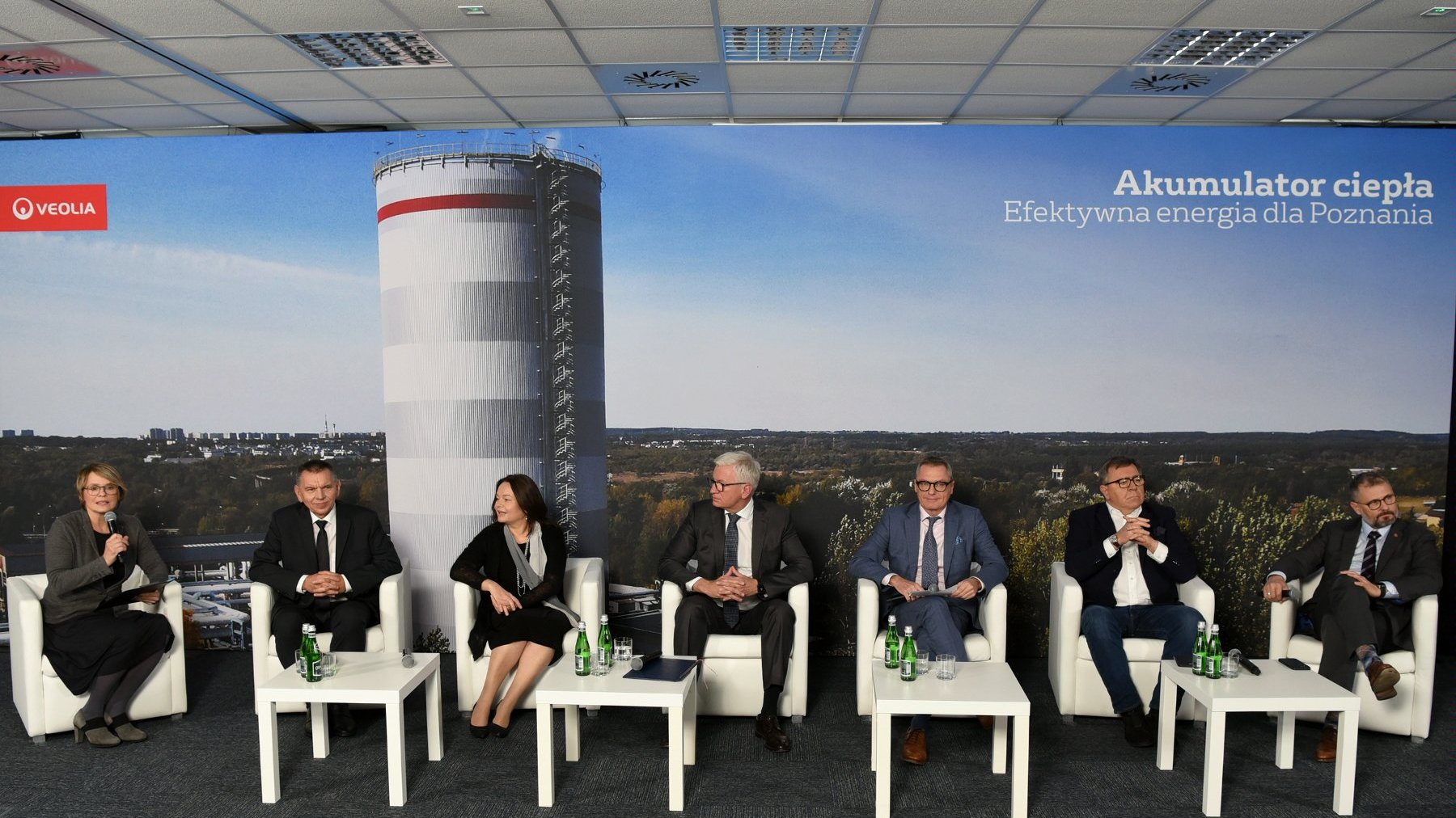 Zdjęcie przedstawia uczestników konferencji na tle zdjęcia akumulatora.