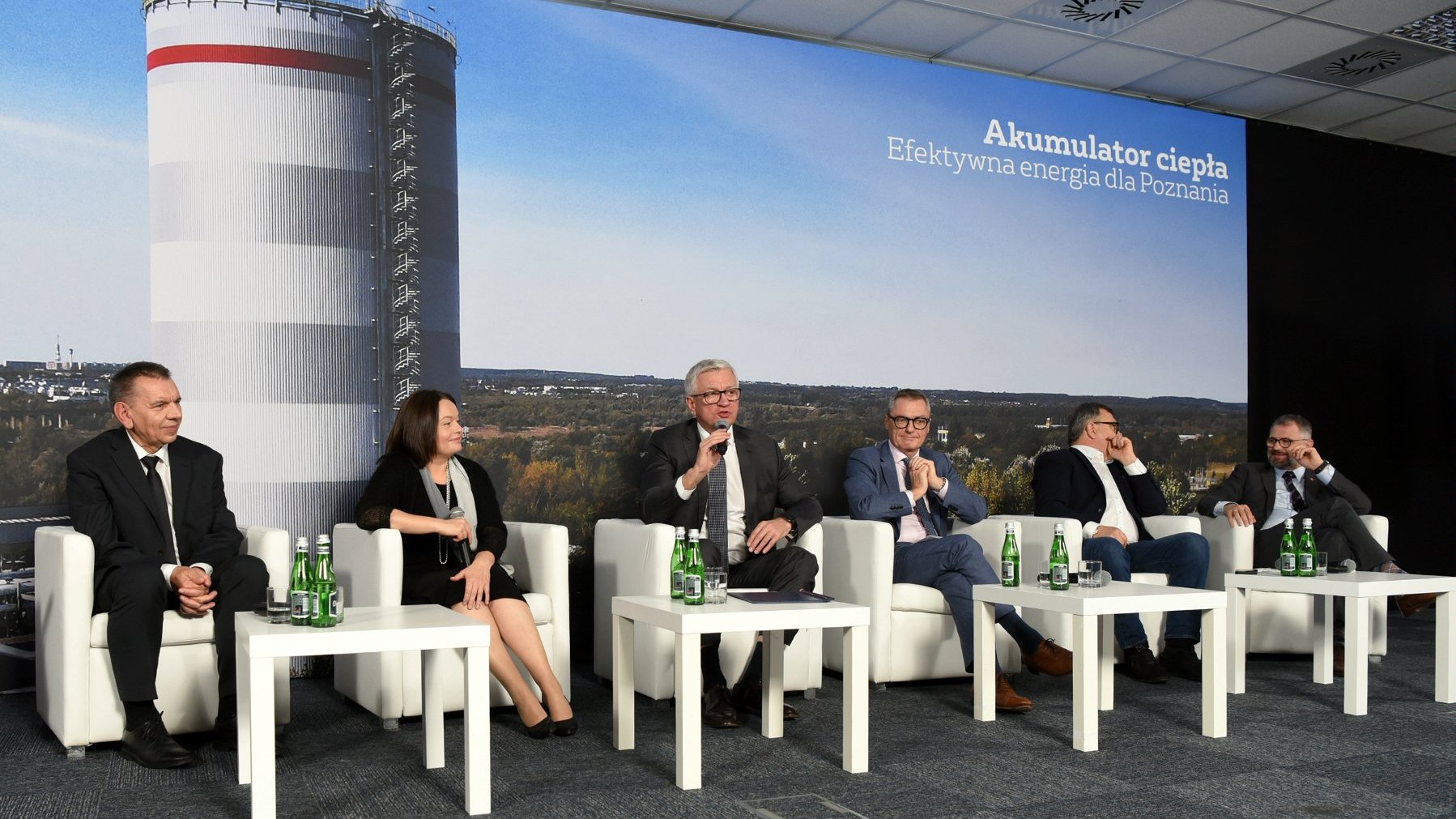 Zdjęcie przedstawia uczestników konferencji na tle zdjęcia akumulatora.