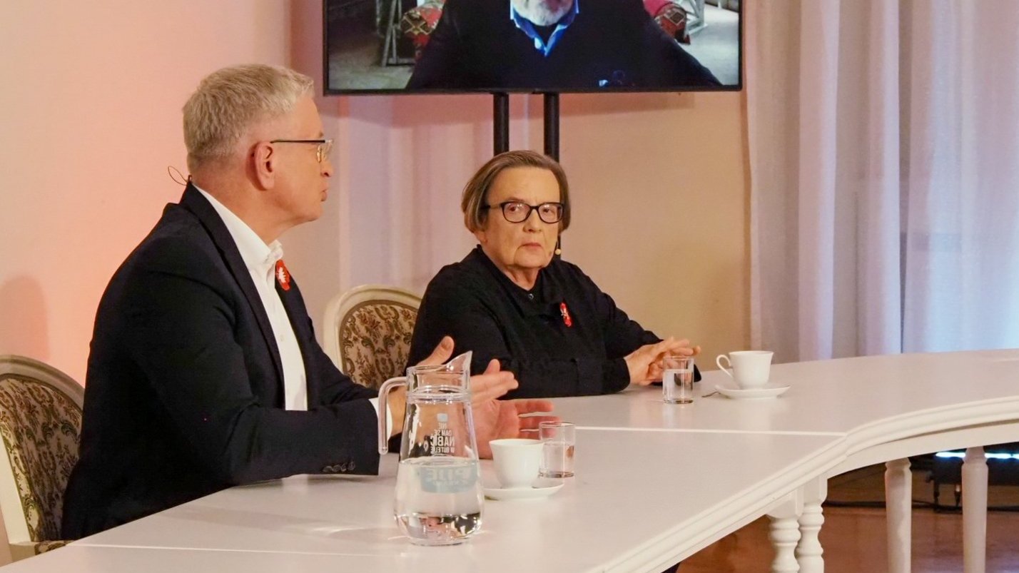 Na zdjęciu uczestnicy debaty, na pierwszym planie Jacek Jaśkowiak, obok niego Agnieszka Holland, nad nimi ekran, na nim Aleksander Kwaśniewski