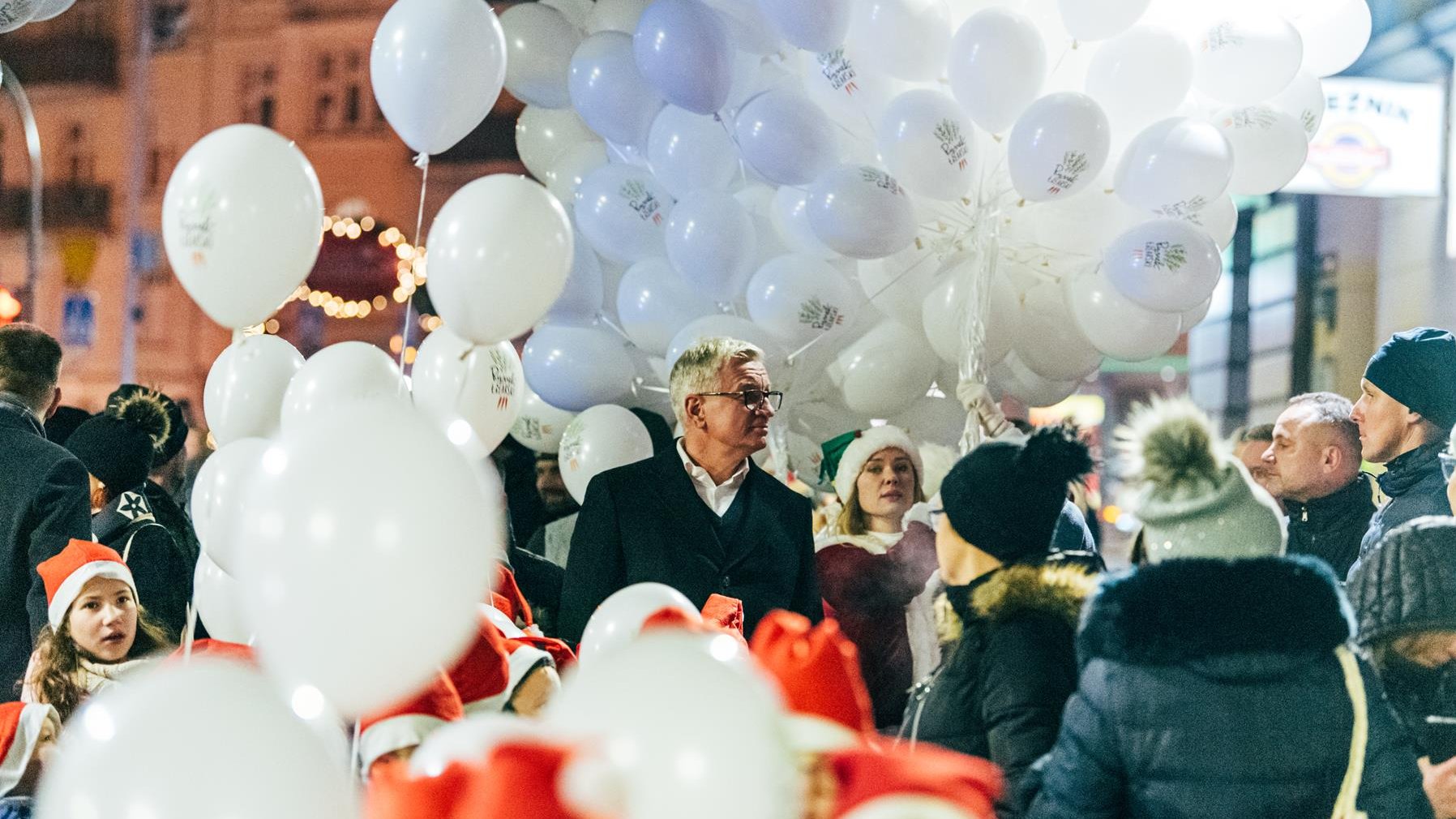 Na zdjęciu grupa ludzi, w niej Jacek Jaśkowiak, prezydent Poznania, w tle i wokół dużo białycch balonów