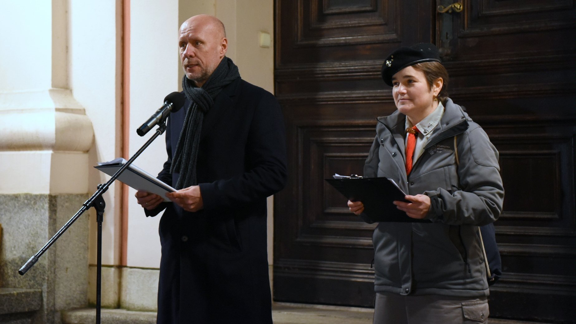 Zdjęcie przedstawia wiceprezydenta Gussa przed mikrofonem na schodach dziedzińca.