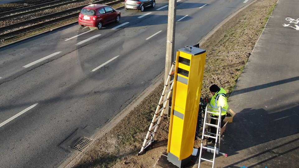 Sznur samochodów na ul. Hetmańskiej. Na poboczu trwa montaż fotoradaru.