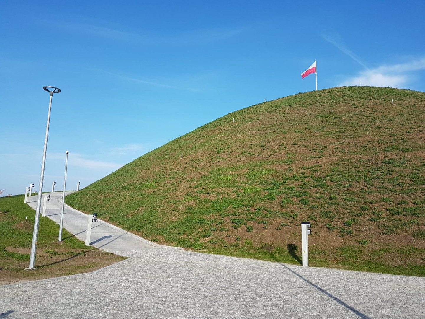 Kopiec Wolności z biało-czerwoną flagą na szczycie - grafika artykułu