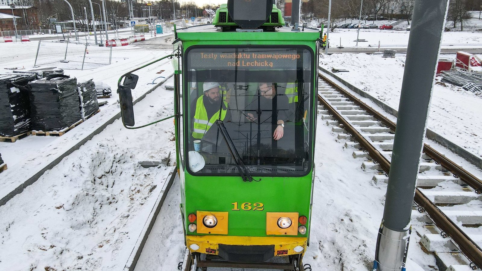 Tramwaj na torowisku, wokół śnieg, obok sieć trakcyjna