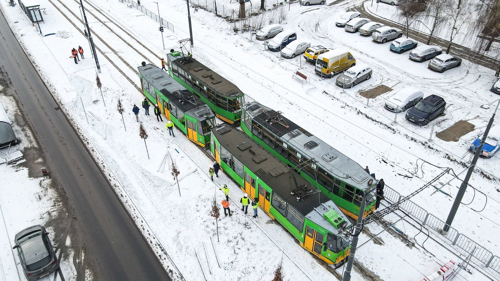 Tramwaj widziany z lotu ptaka, przy nim dużo ludzi, obok parking