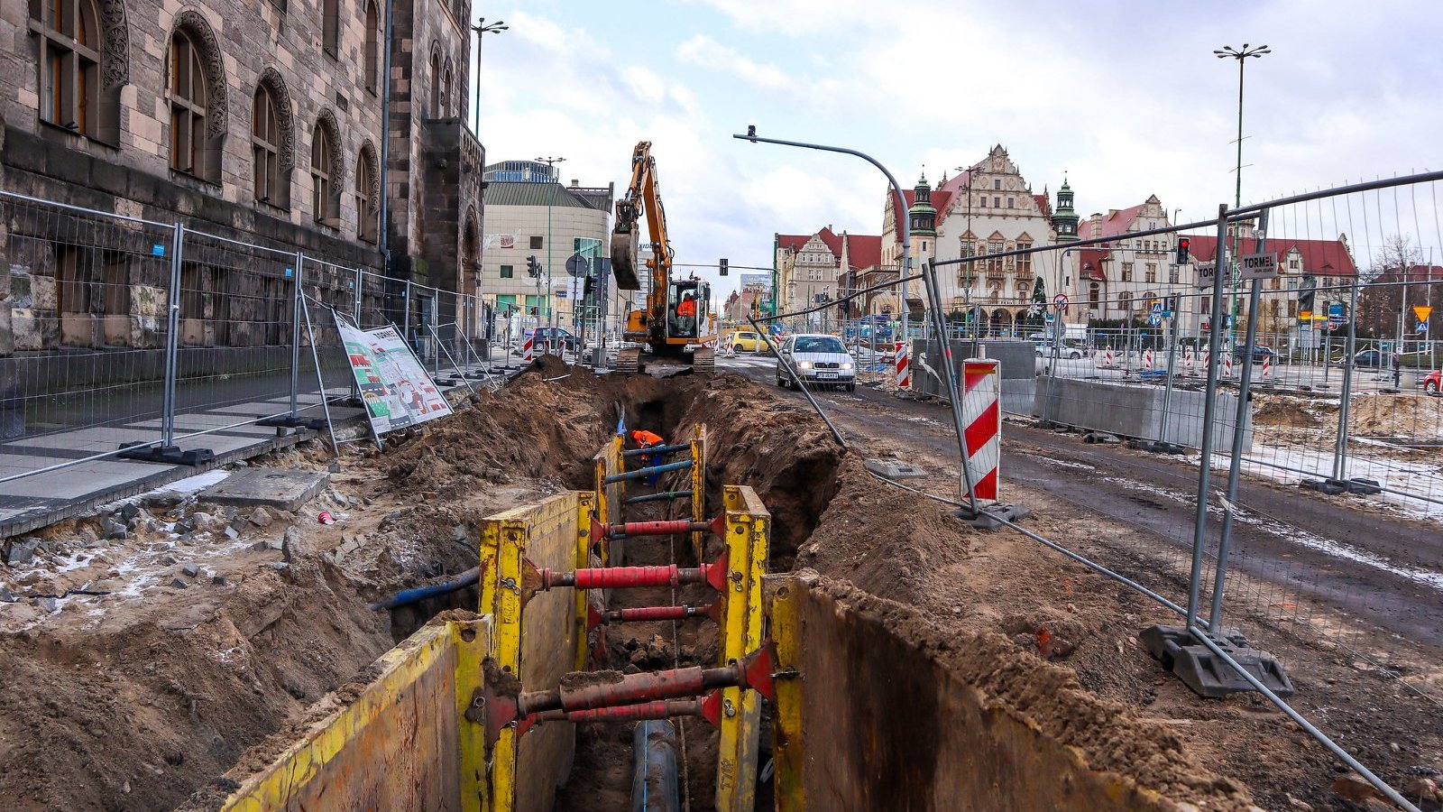 Na zdjęciu przebudowa ulicy Święty Marcin, na pierwszym planie rów, za nim koparka, w tle budynek uniwersytetu