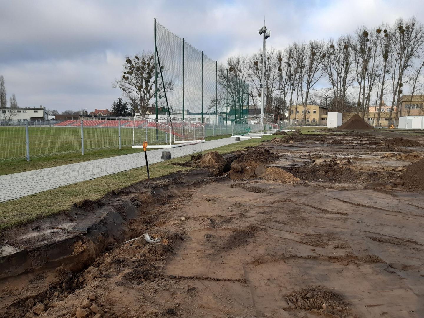 Galeria zdjęć przedstawia prace budowlane nad nowym boiskiem. Widać na nich hałdy ziemi, maszyny budowlane i pracowników. - grafika artykułu