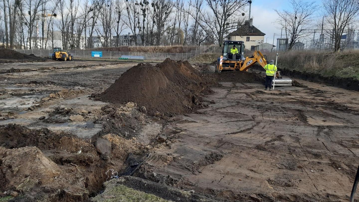 Galeria zdjęć przedstawia prace budowlane nad nowym boiskiem. Widać na nich hałdy ziemi, maszyny budowlane i pracowników.