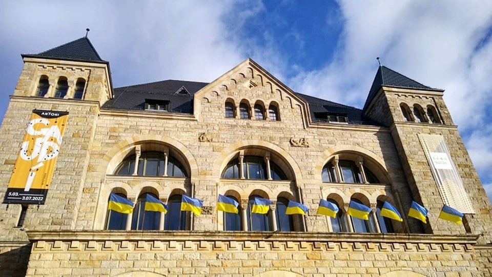 Zdjęcie przedstawia flagi Ukrainy powiewające na budynku CK Zamek.