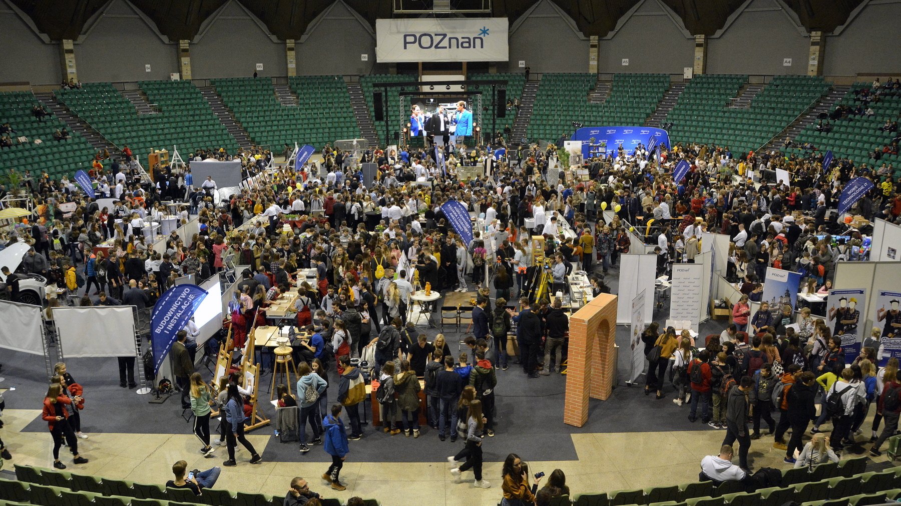 Zdjęcie przedstawia tłum ludzi we wnętrzu hali Arena. - grafika artykułu