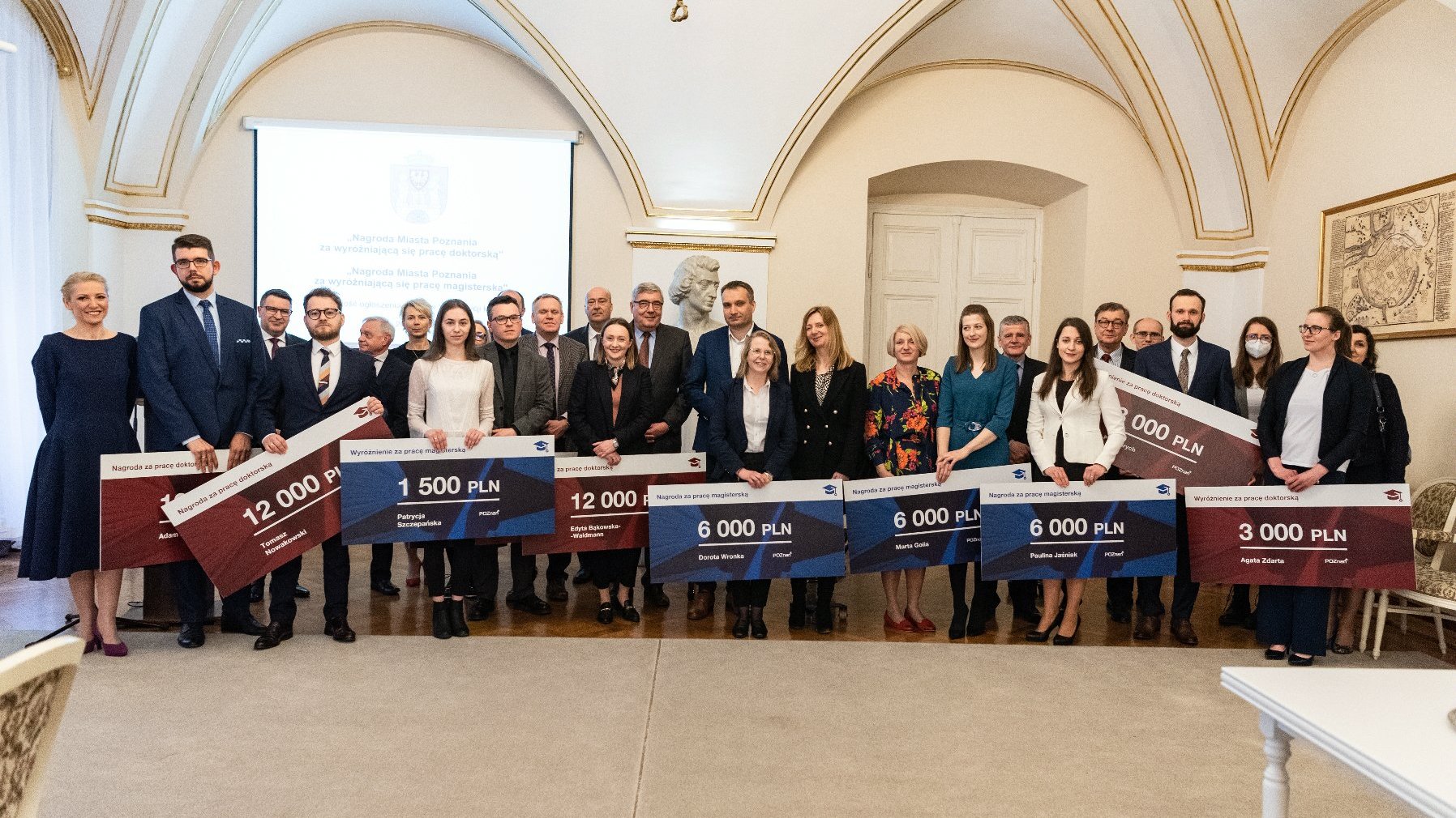 Galeria zdjęć przedstawia wręczenie nagród w sali urzędu miasta. Widać na nich wiceprezydenta Poznania i przewodniczącego Rady Miasta Poznania oraz laureatów.