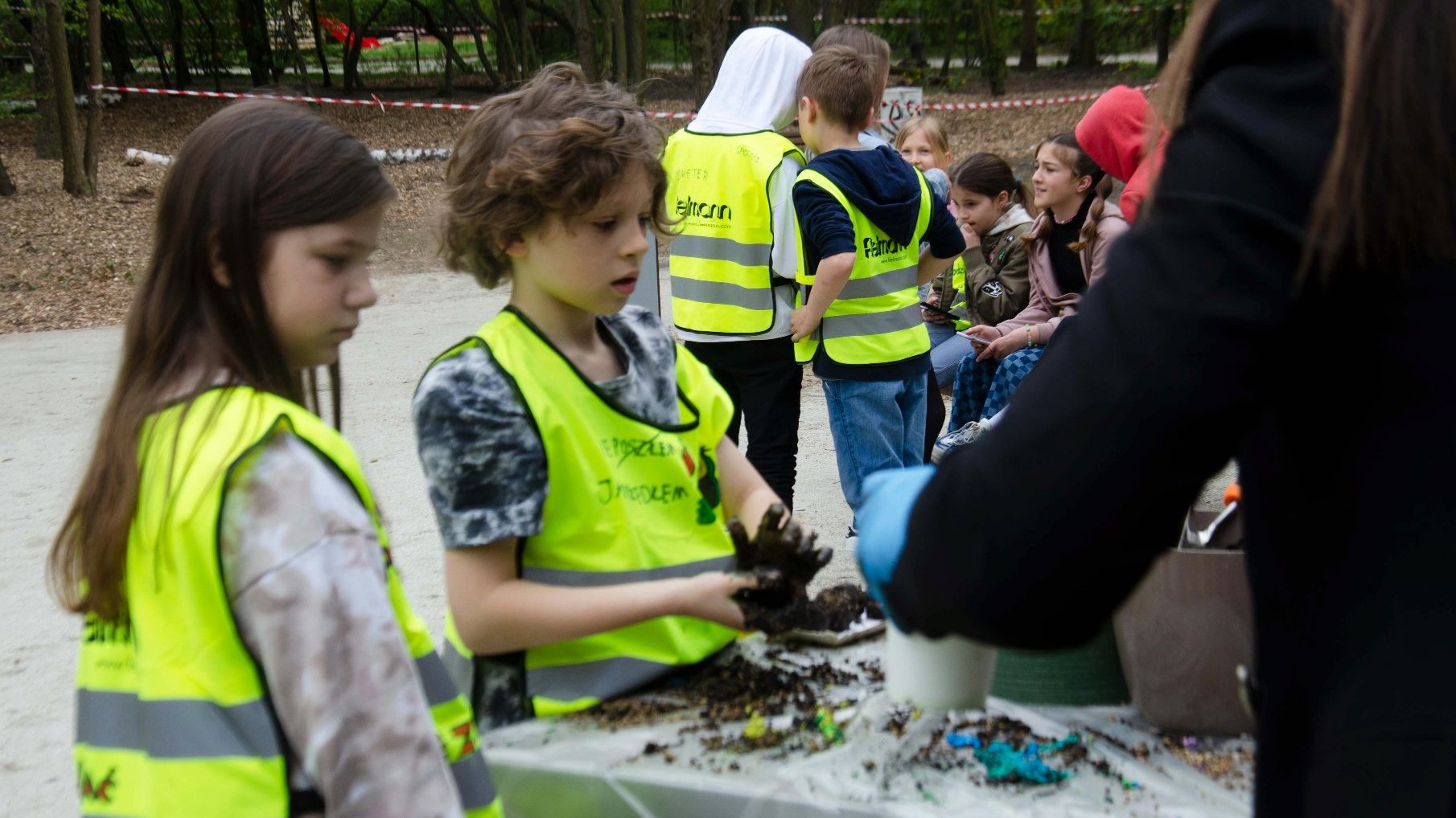 Galeria zdjęć przedstawia dzieci podczas ekowarsztatów na terenie zieleńca.