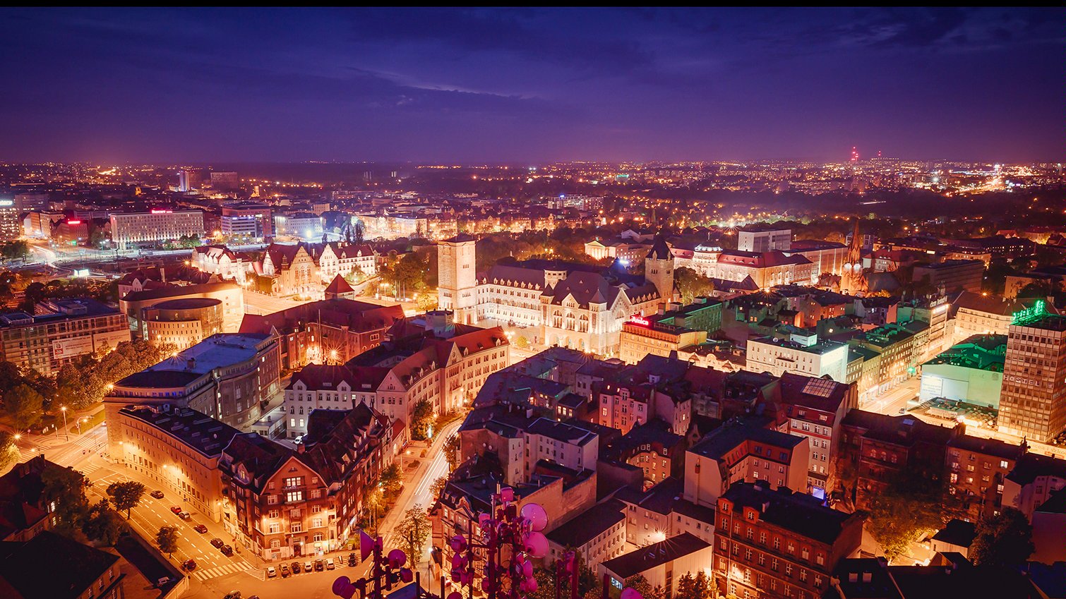 Na zdjęciu panorama Poznania po zmroku, w centrum zabudowa śródmiejska widziana z lotu ptaka - grafika artykułu