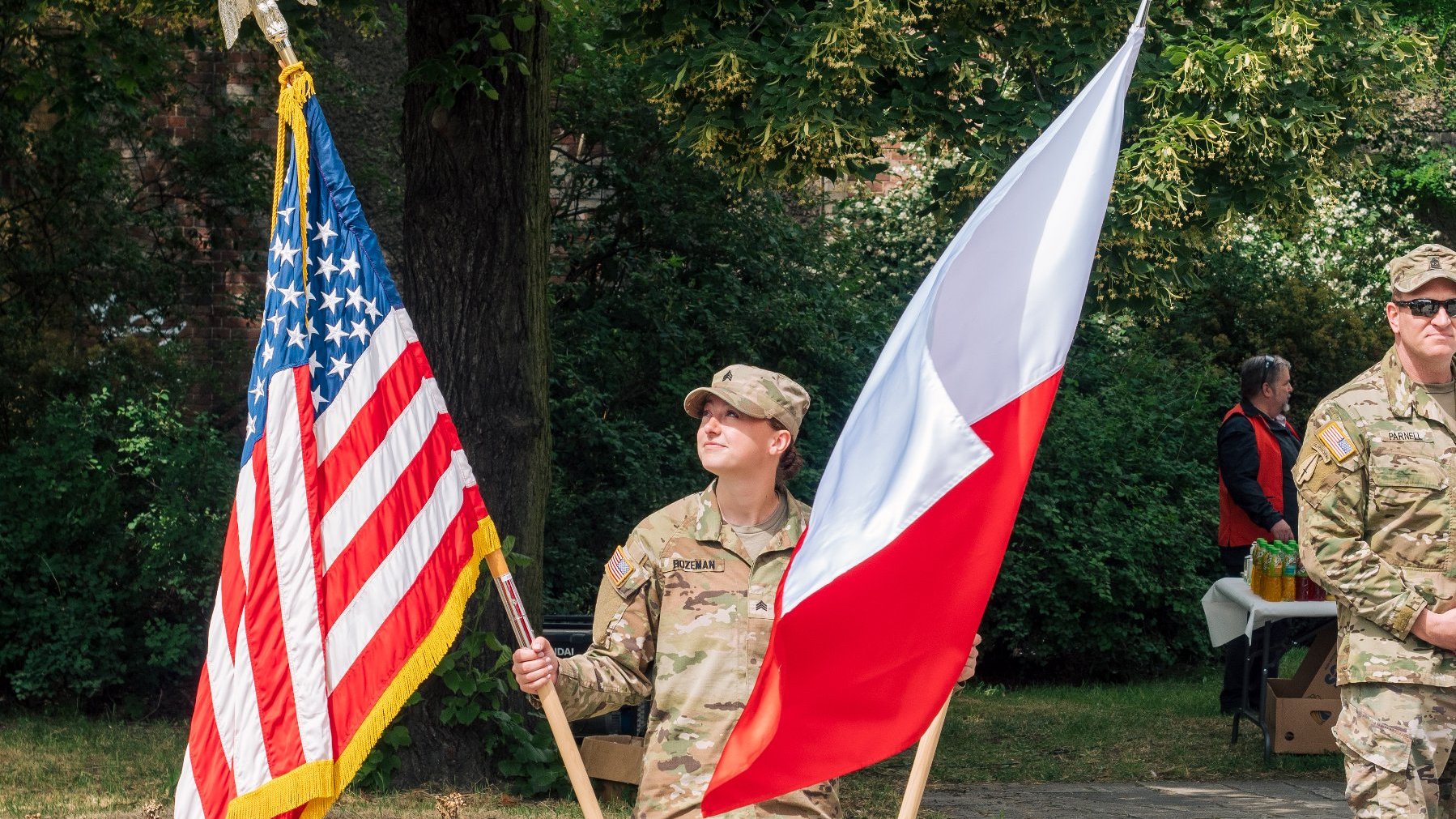 Na zdjęciu żołnierka trzymająca dwie flagi, amerykańską i polską