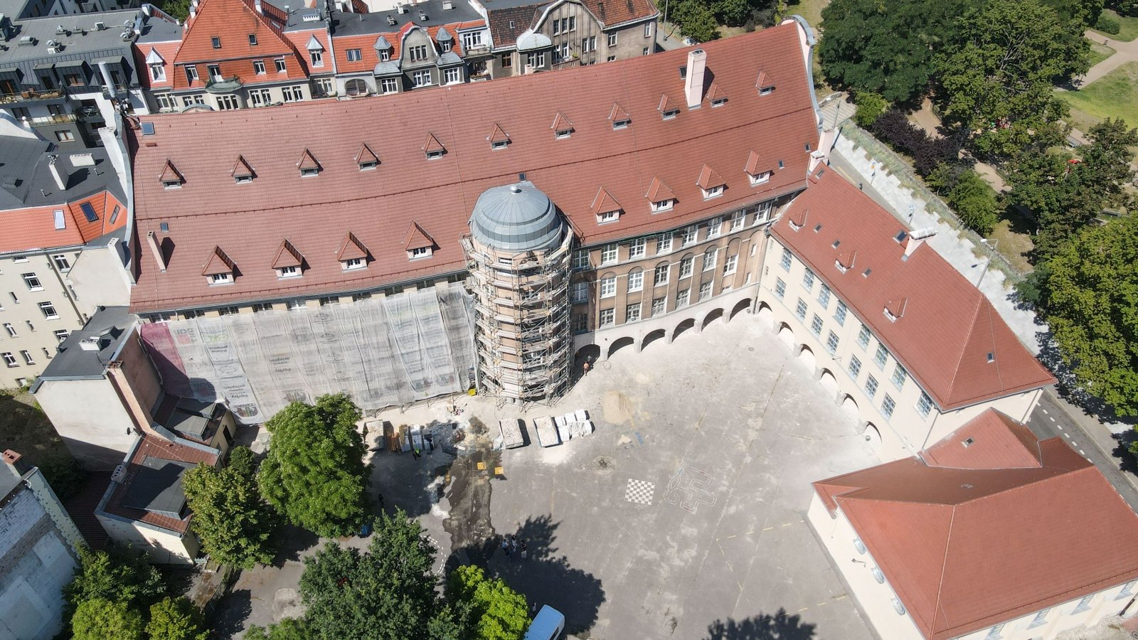 Zdjęcie pokazuje dziedziniec szkoły przy ul. Różanej. Po prawej stronie elewacja niższego budynku została już odnowiona. Teraz zasłonięta jest część po lewej od wieżyczki