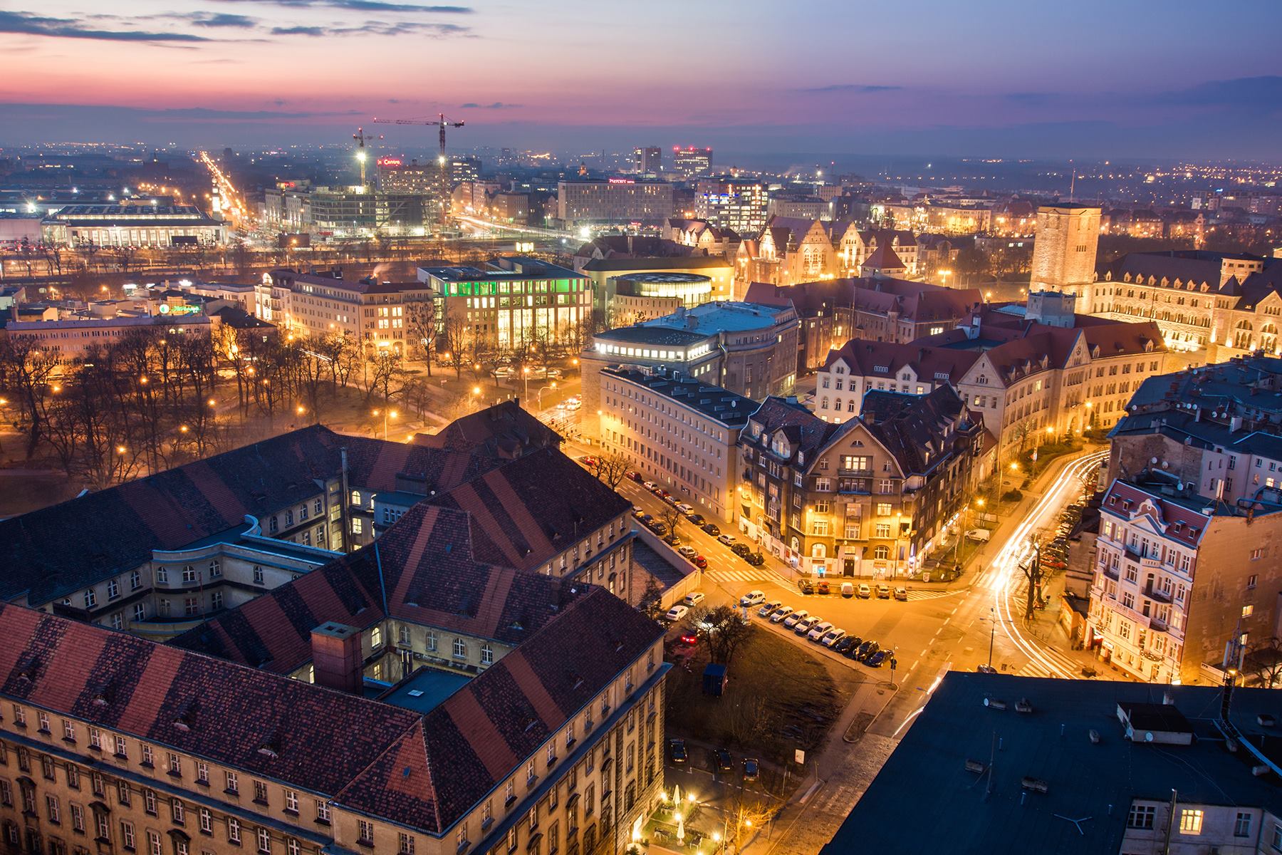 Na zdjęciu panorama Poznania o zmroku, widać dachy kamienic i Okrąglak - grafika artykułu