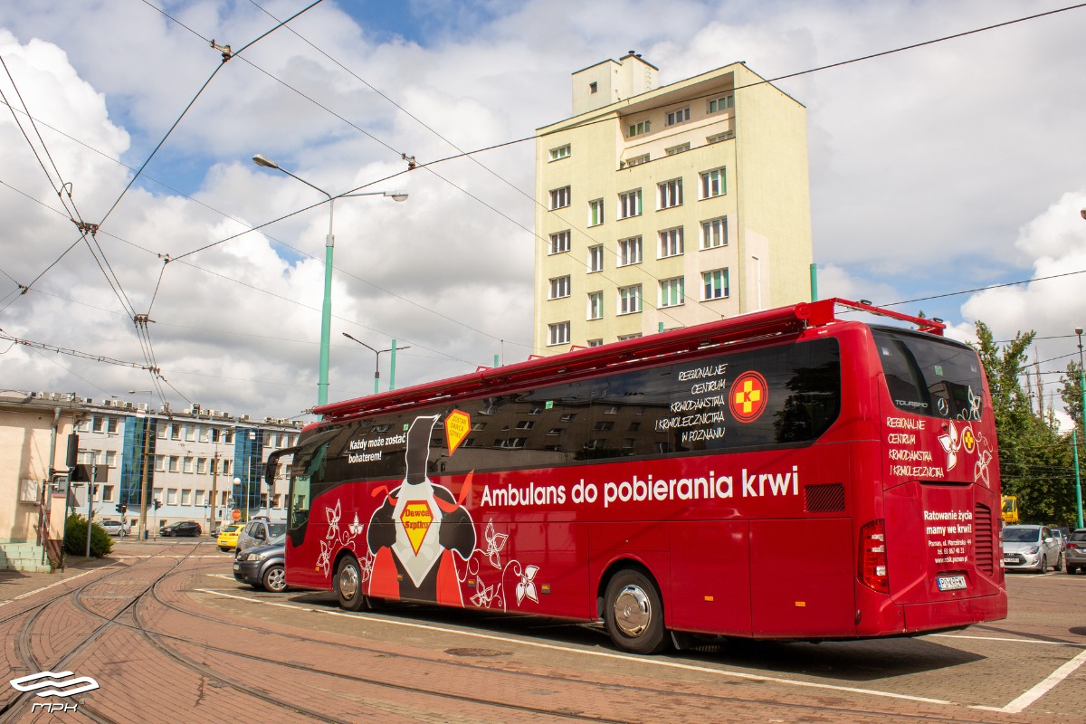 Na pierwszym planie widać czerowny autobus. W tle budynki. - grafika artykułu