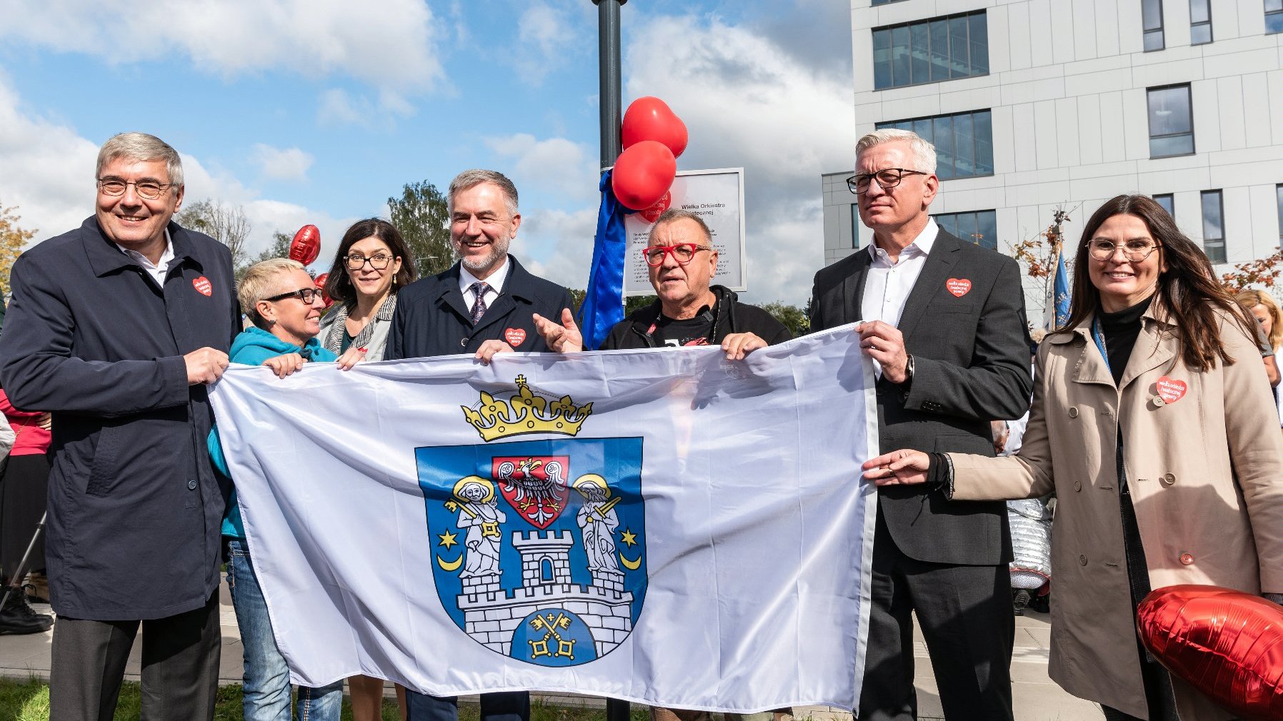 Na zdjęciu samorządowcy oraz Jurek Owsiak, wszyscy trzymają flagę Poznania