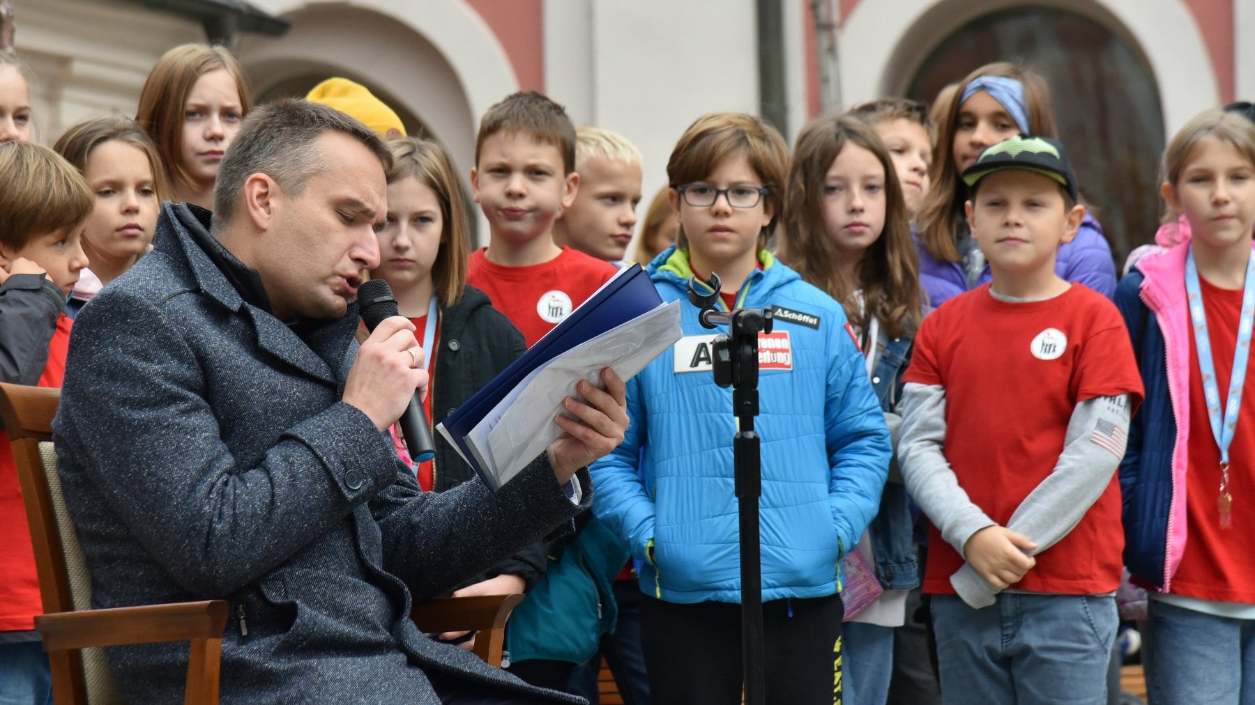 Na zdjęciu Mariusz Wiśniewski, zastępca prezydenta Poznania, czytający tekst, za nim dzieci