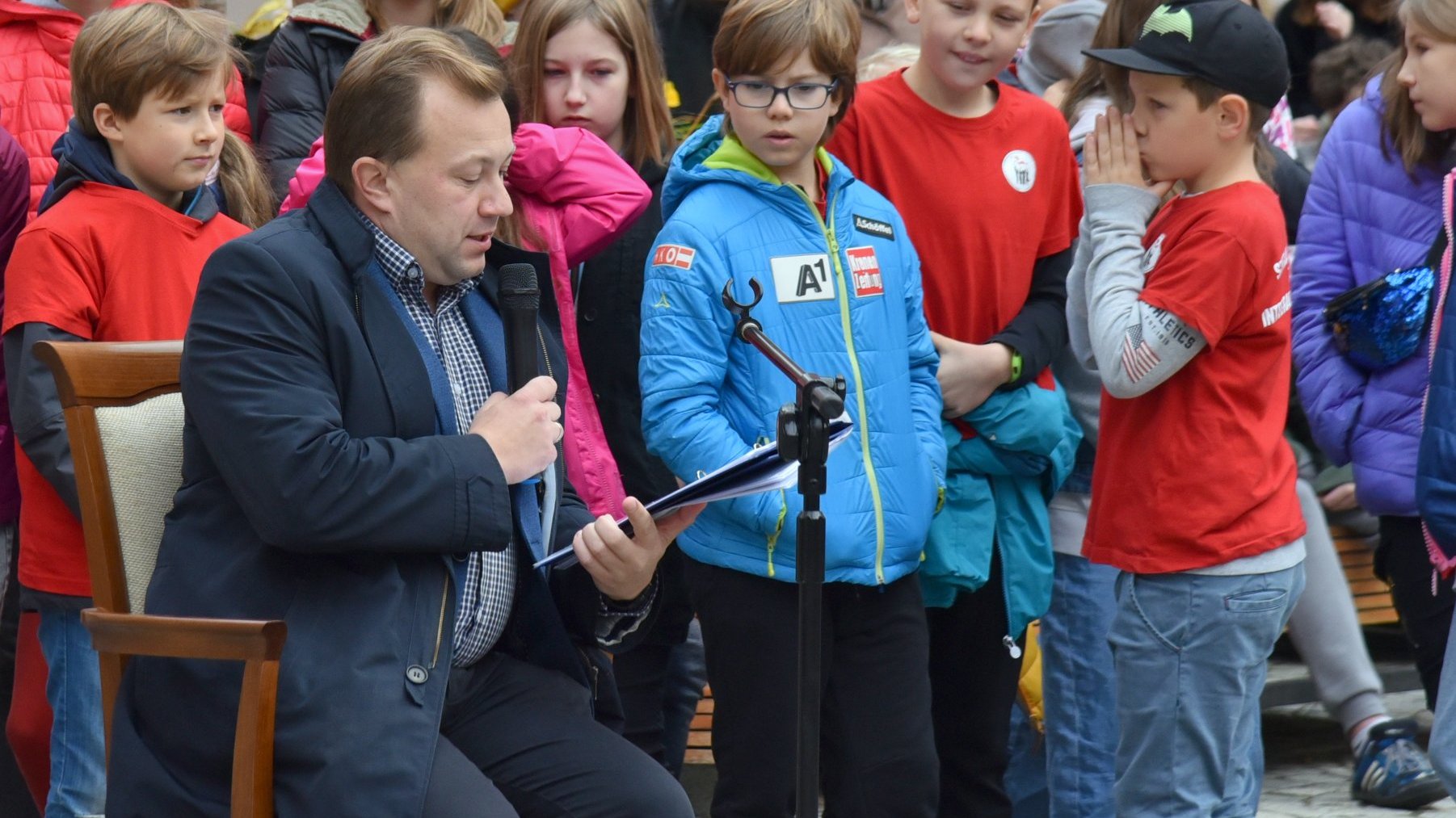 Na zdjęciu radny czytający dzieciom, za nim przypatrujący się mu uczniowie