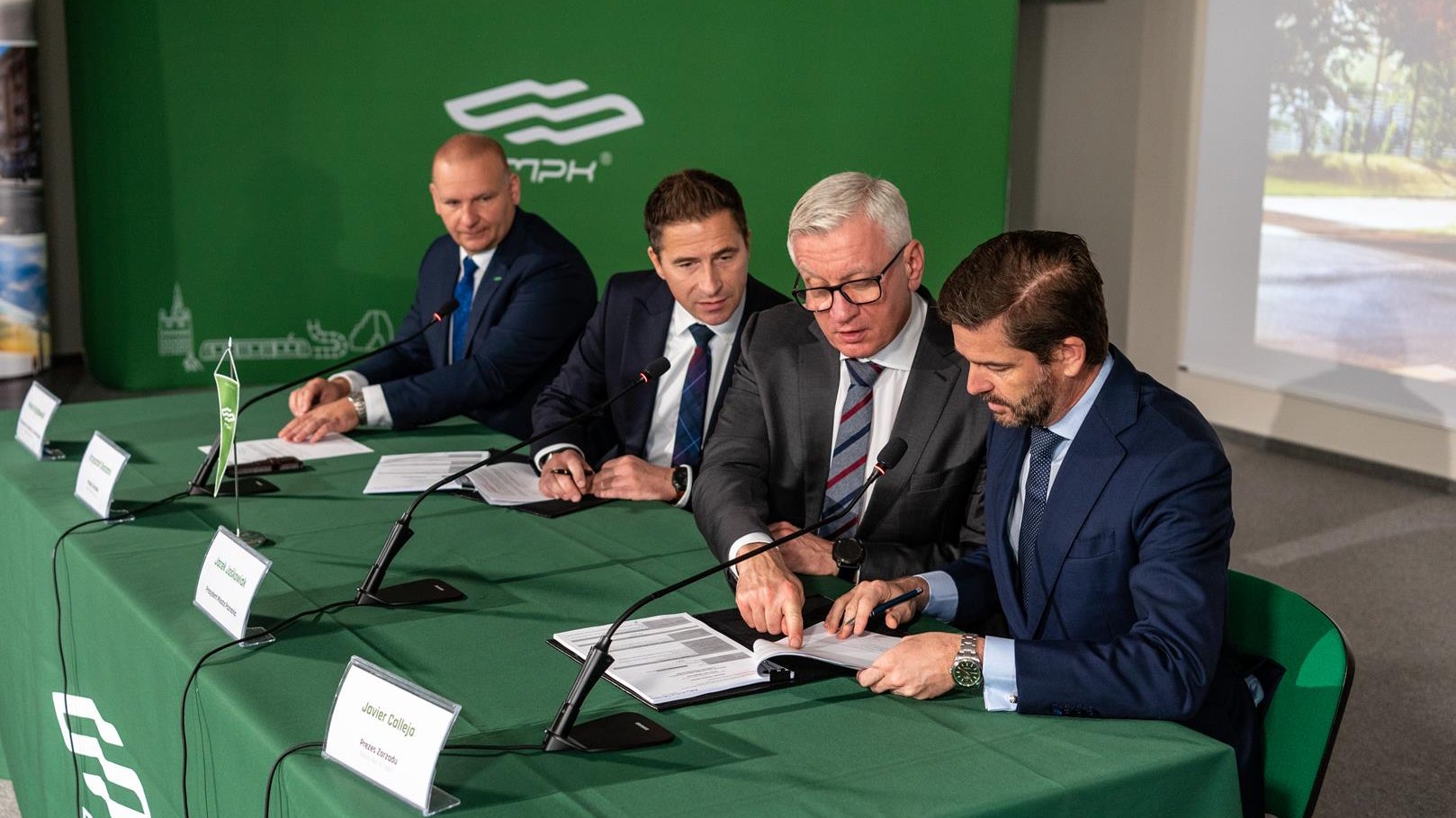 Na zdjęciu czterej mężczyźni przy stole, podpisują umowę