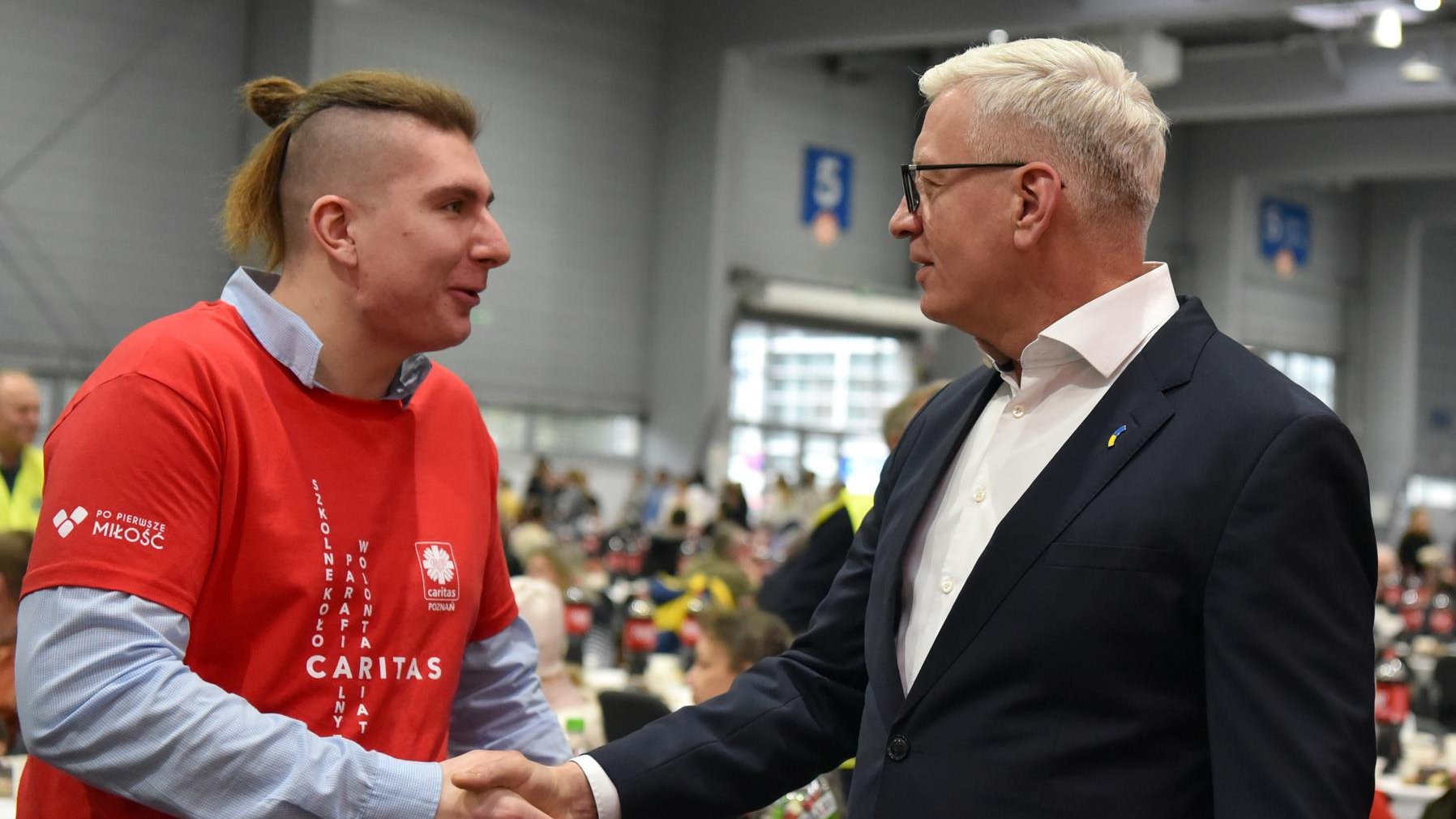 Na zdjęciu prezydent Poznania podający dłoń wolontariuszowi Caritas