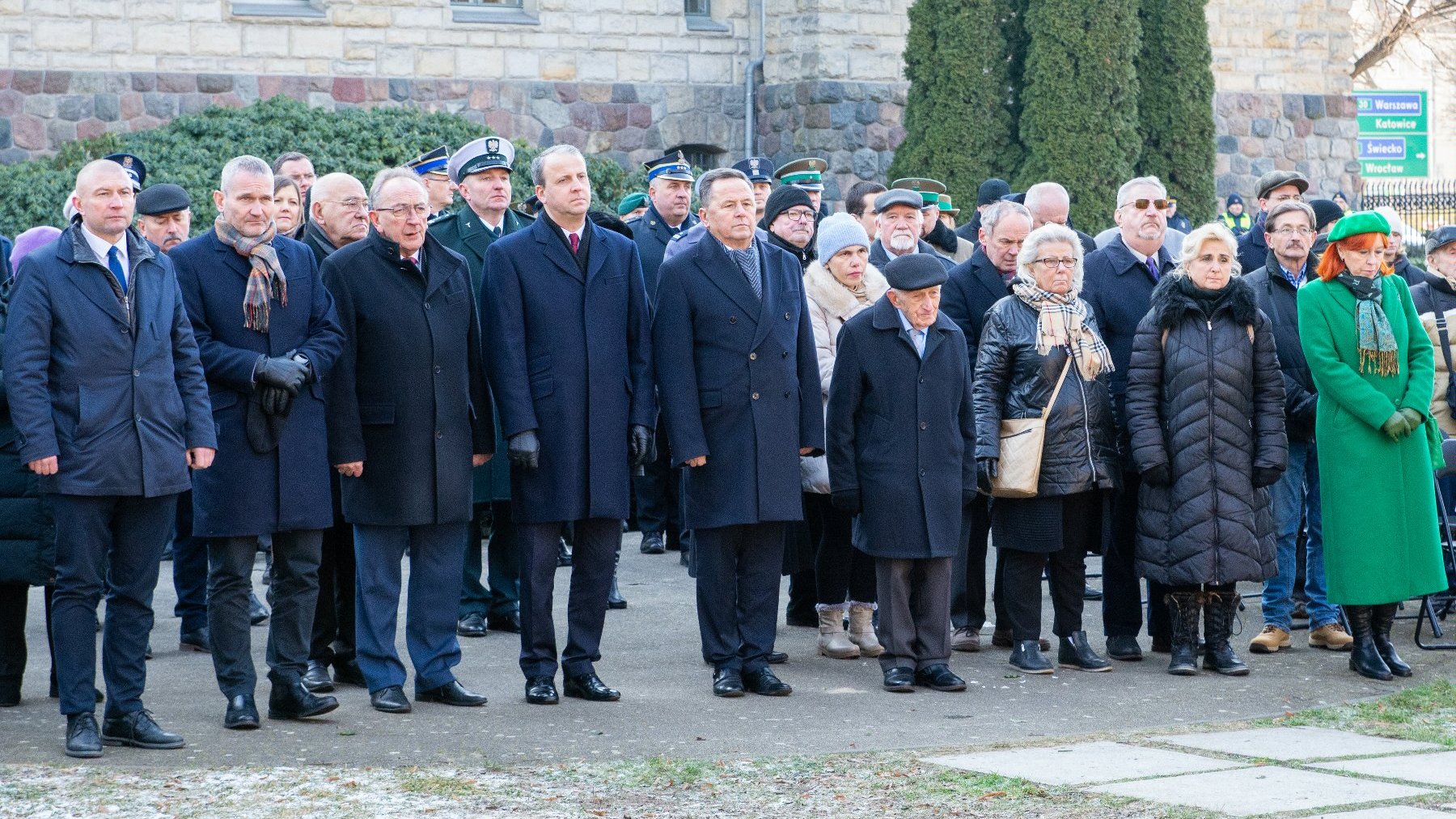 Na zdjęciu grupa ludzi stojących przed pomnikiem