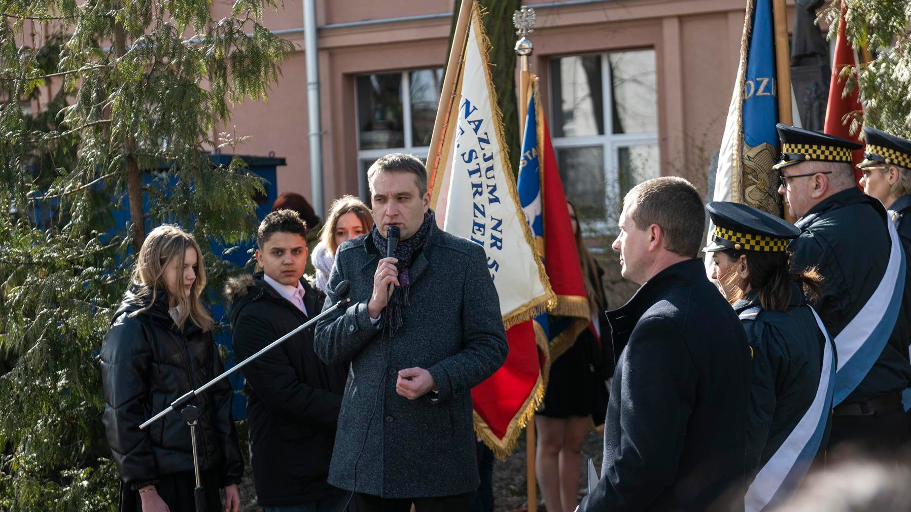 Na zdjęciu zastępca prezydenta Poznania przy mikrofonie, w tle poczet sztandarowy