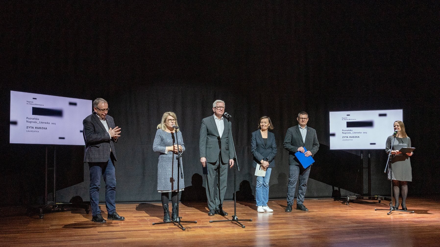 Grupa osób stoi na scenie, wśród nich m.in. Jacek Jaśkowiak, prezydent Poznania.