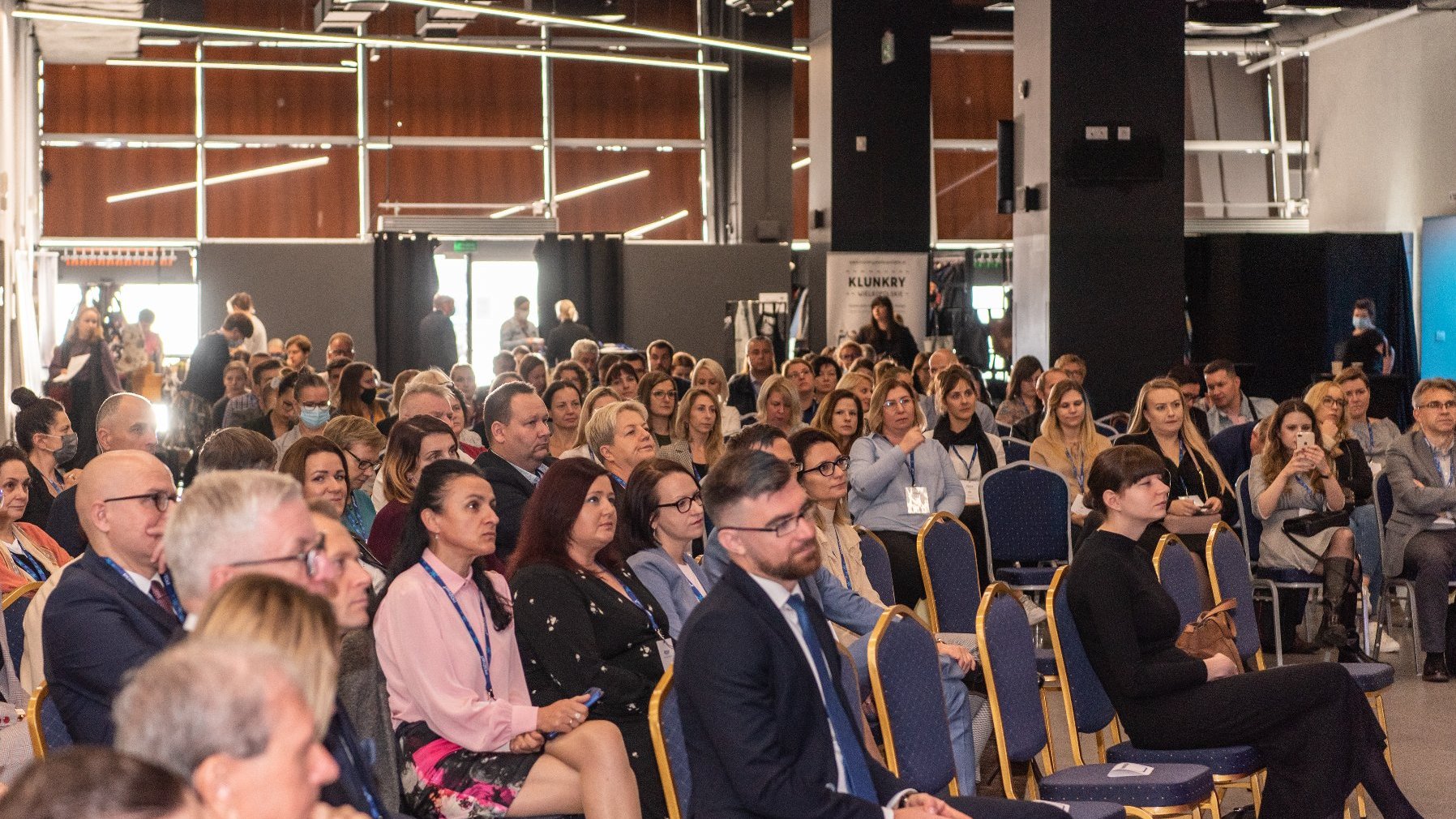 Na zdjęciu uczestnicy konferencji, siedzą na krzesłach, słuchają wystąpienia