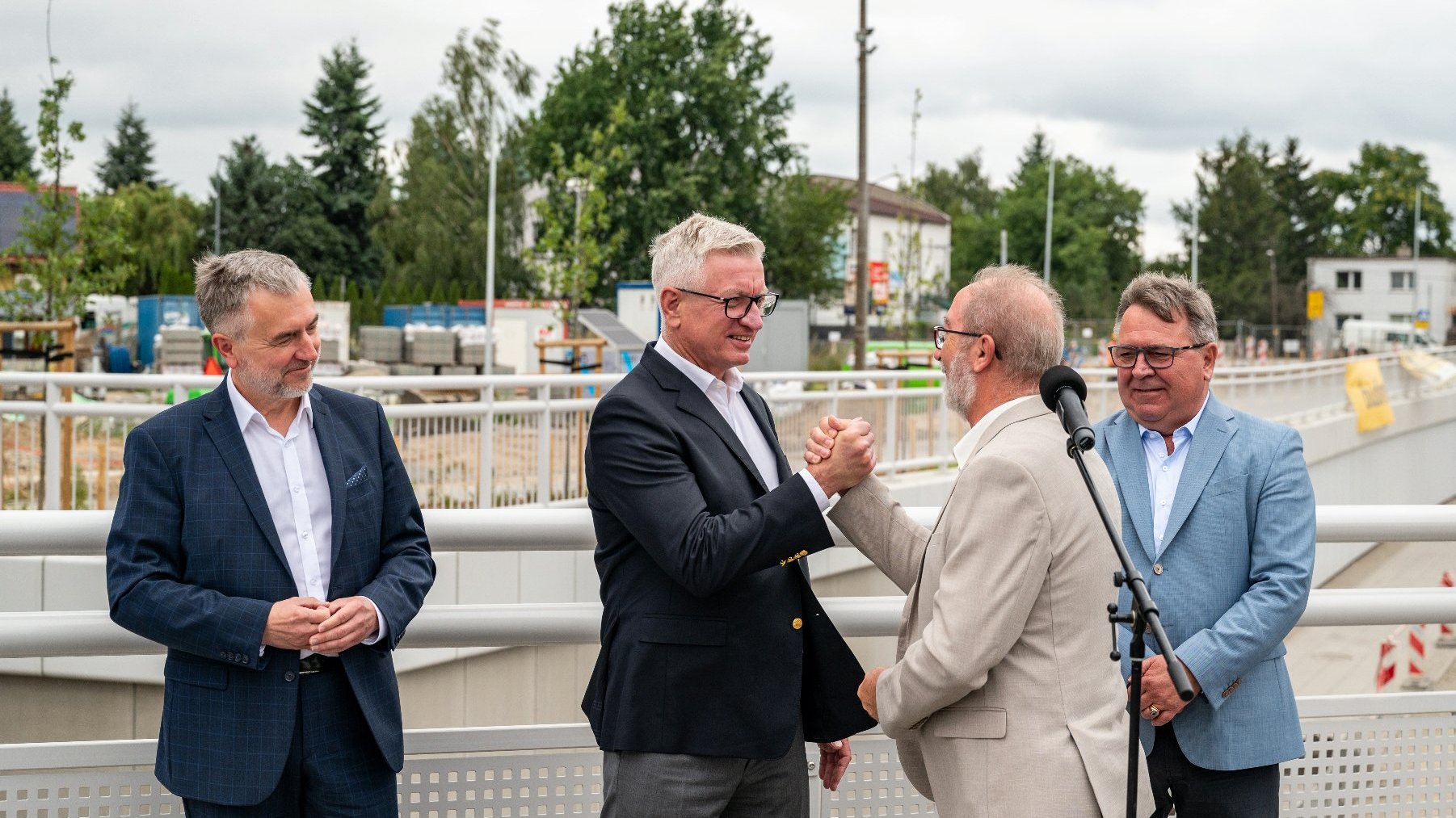 Na zdjęciu czterej mężczyźni, dwóch z nich podaje sobie ręce