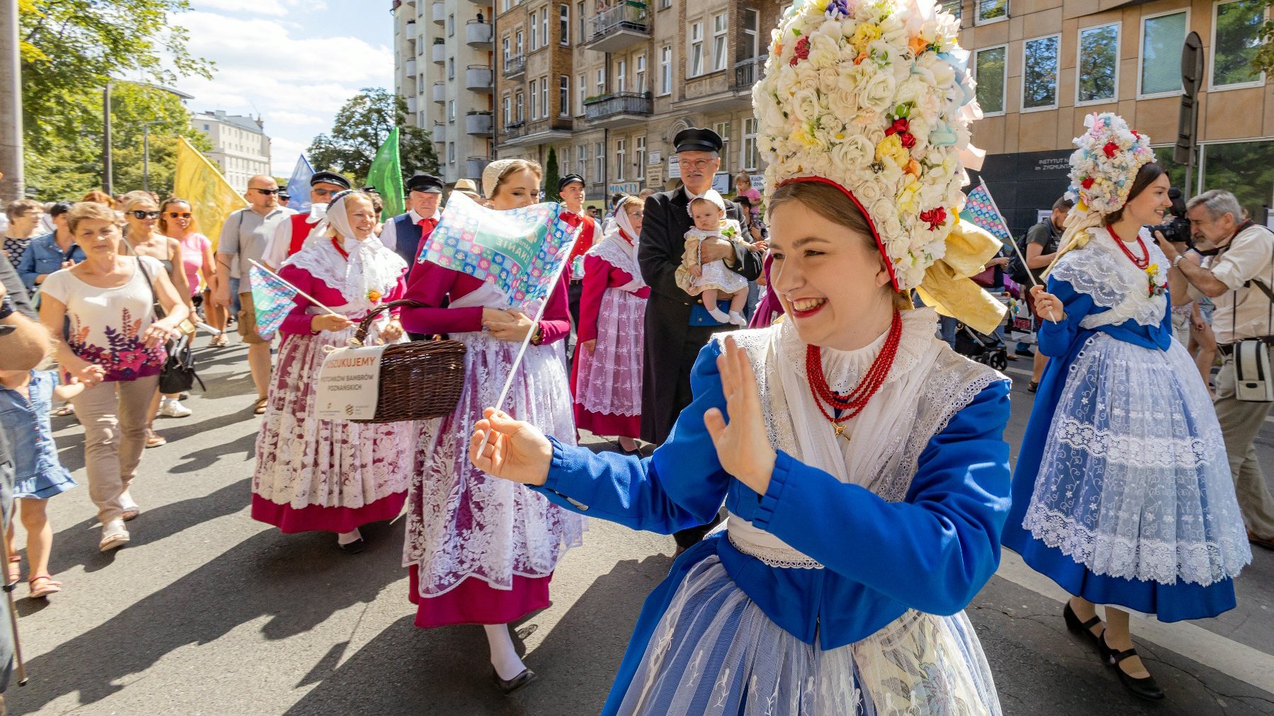 Na zdjęciu korowód Bambrów, na pierwszym planie uśmiechnięta dziewczyna w tradycyjnym stroju