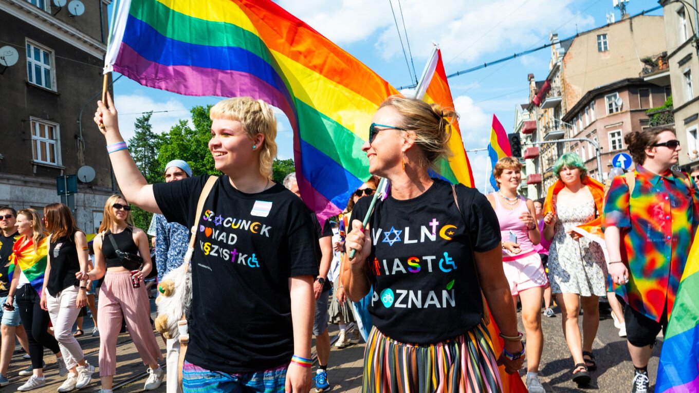 Na zdjęciu dwie osoby idące w Marszu Równości w miejskich koszulkach