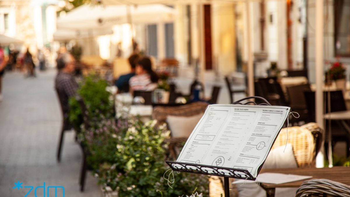 Na zdjeciu ogródek gastronomiczny, na pierwszym planie menu - grafika artykułu