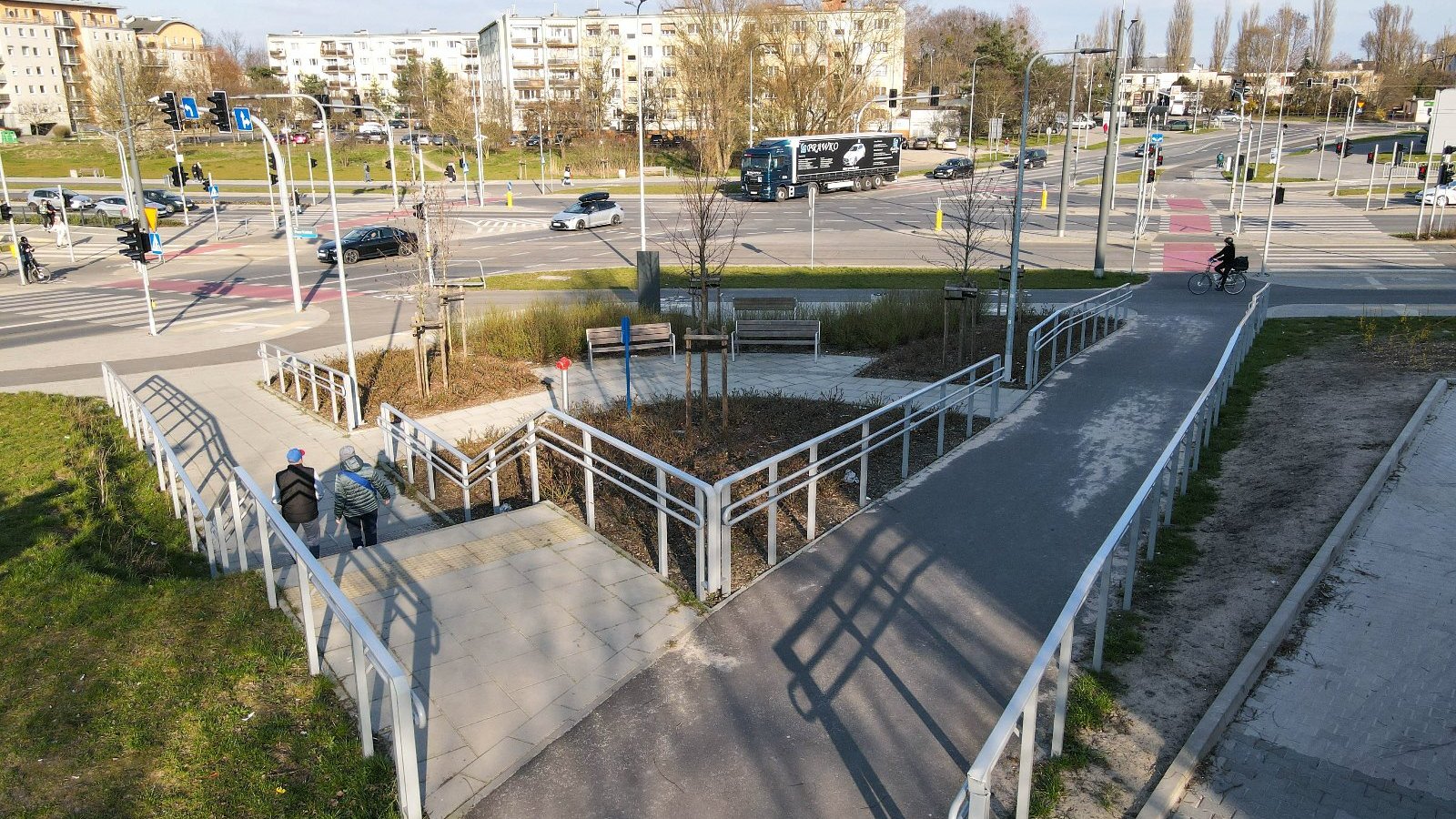 Na zdjęciu widać podjazd dla wózków. W tle jezdnia i poruszające się po niej samochody.