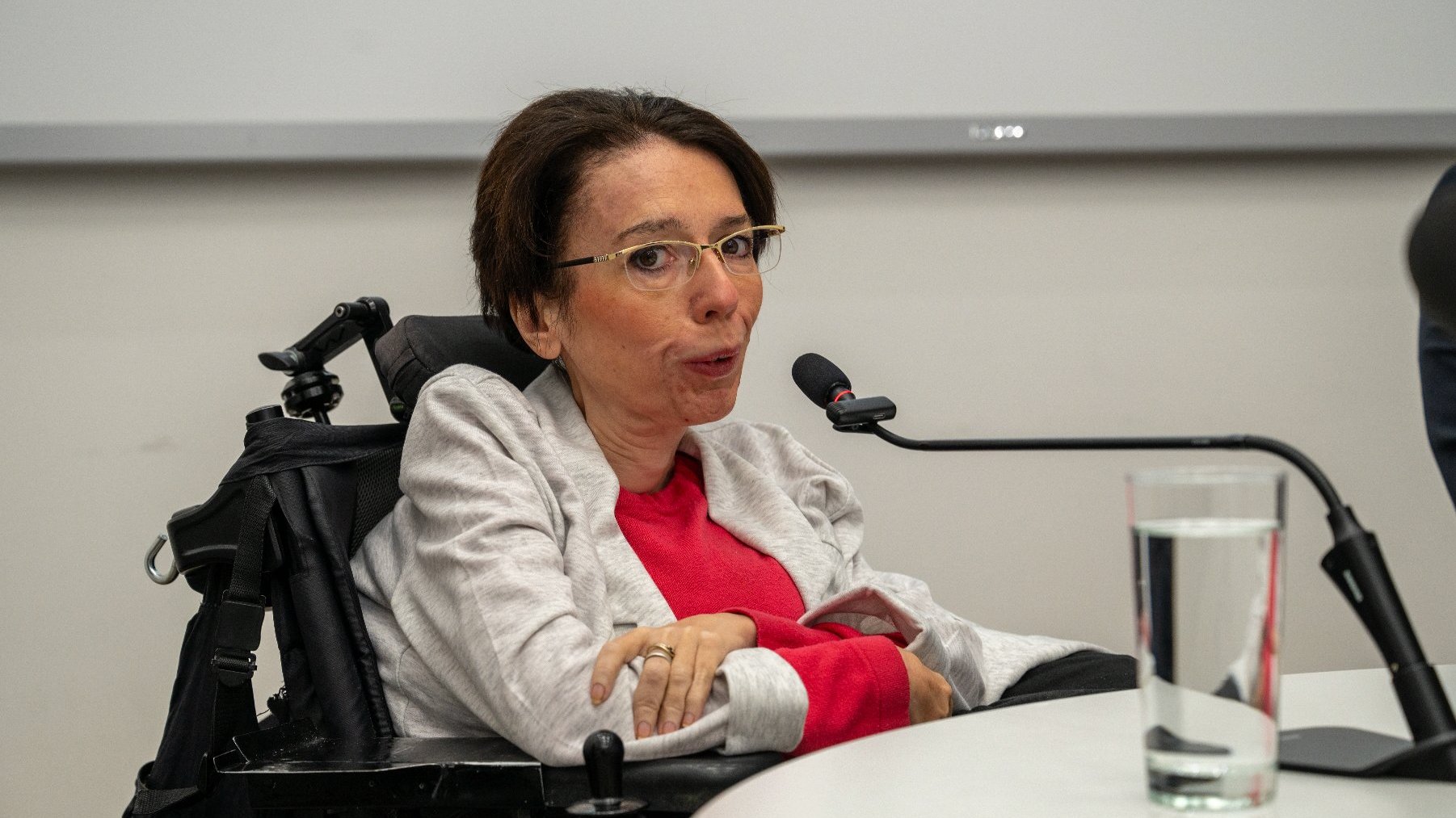 Na zdjęciu kobieta w okularach siedząca za stołem
