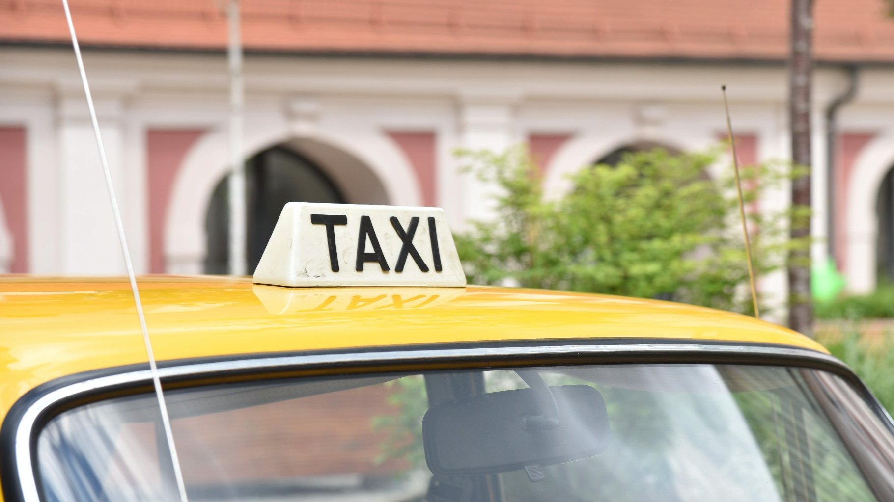 Zdjęcie przedstawia napis taxi na dachu taksówki.