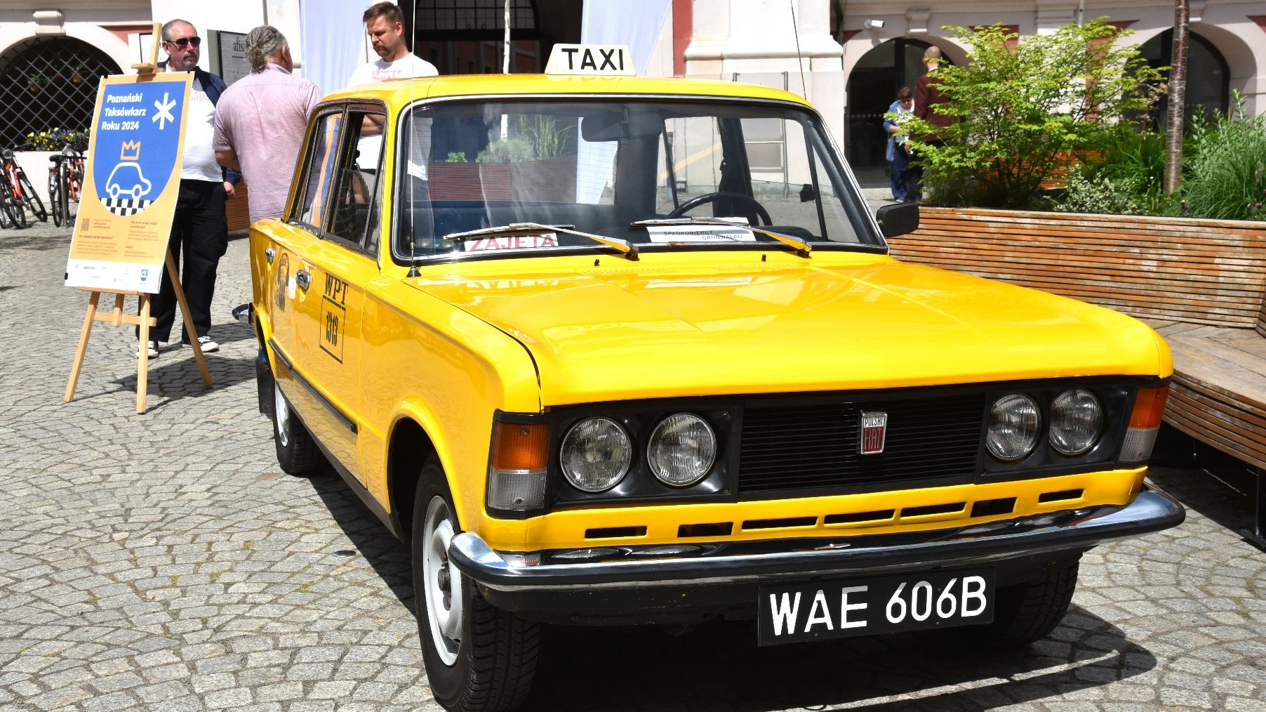 Zdjęcie przedstawia żółtą taksówkę.