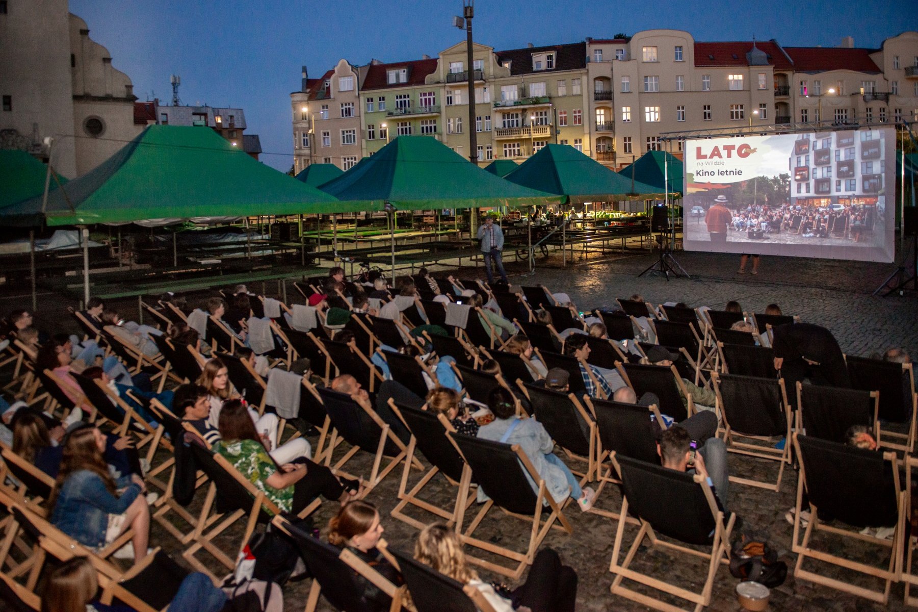 Na zdjęciu widać osoby siedzące na leżakach na rynku Wildeckim i oglądające film na ekrania - grafika artykułu