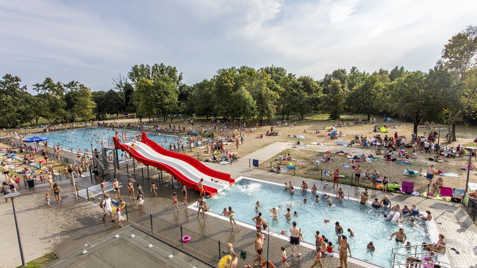 Zdjęcie przedstawia baseny i plażę z lotu ptaka. Widać na nim tłum ludzi.