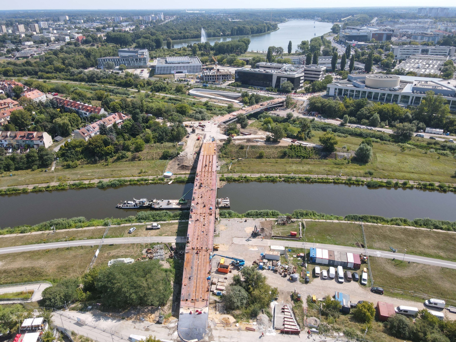 Zdjęcie przedstawia budowane mosty nad rzeką i otaczające budynki widziane z lotu ptaka. - grafika artykułu