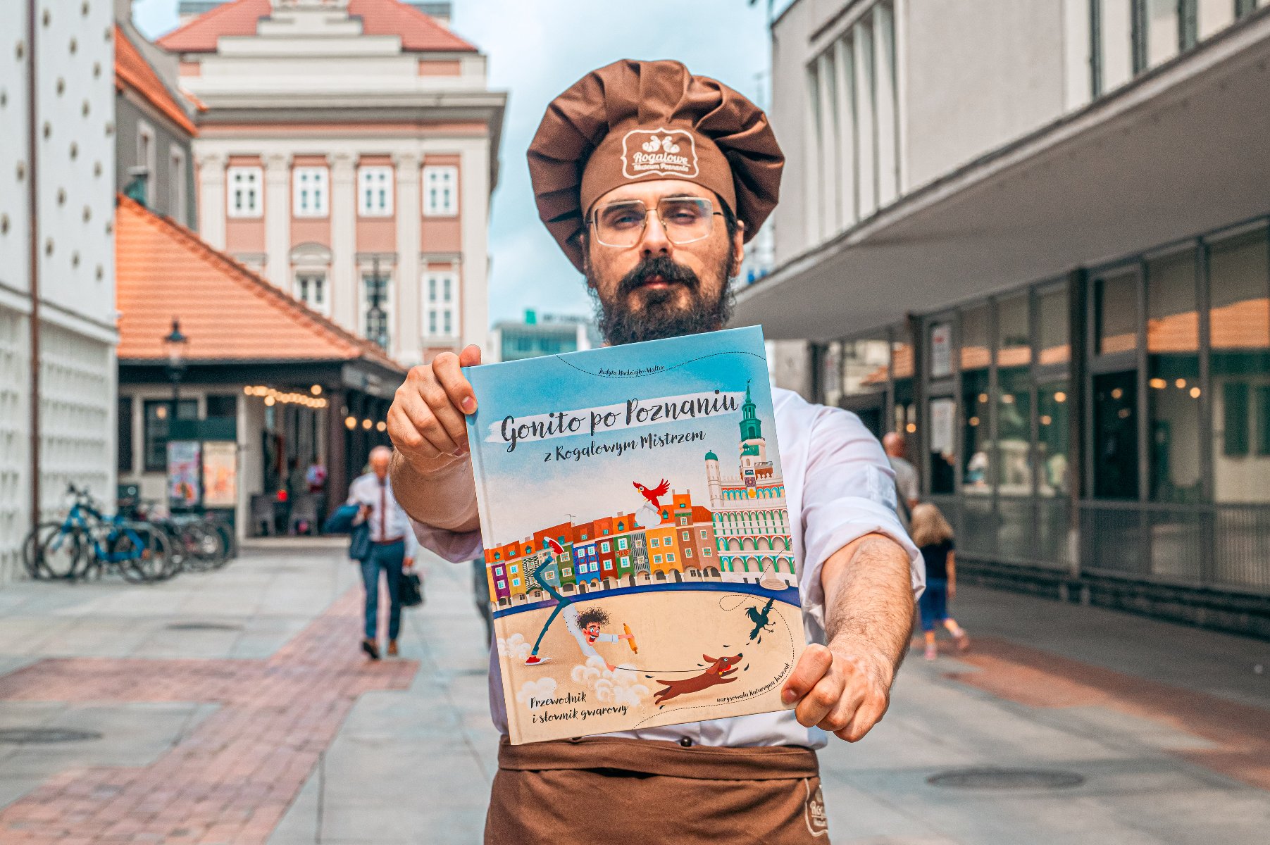 Na zdjęciu mężczyzna w czapce cukiernika trzymający książkę - grafika artykułu