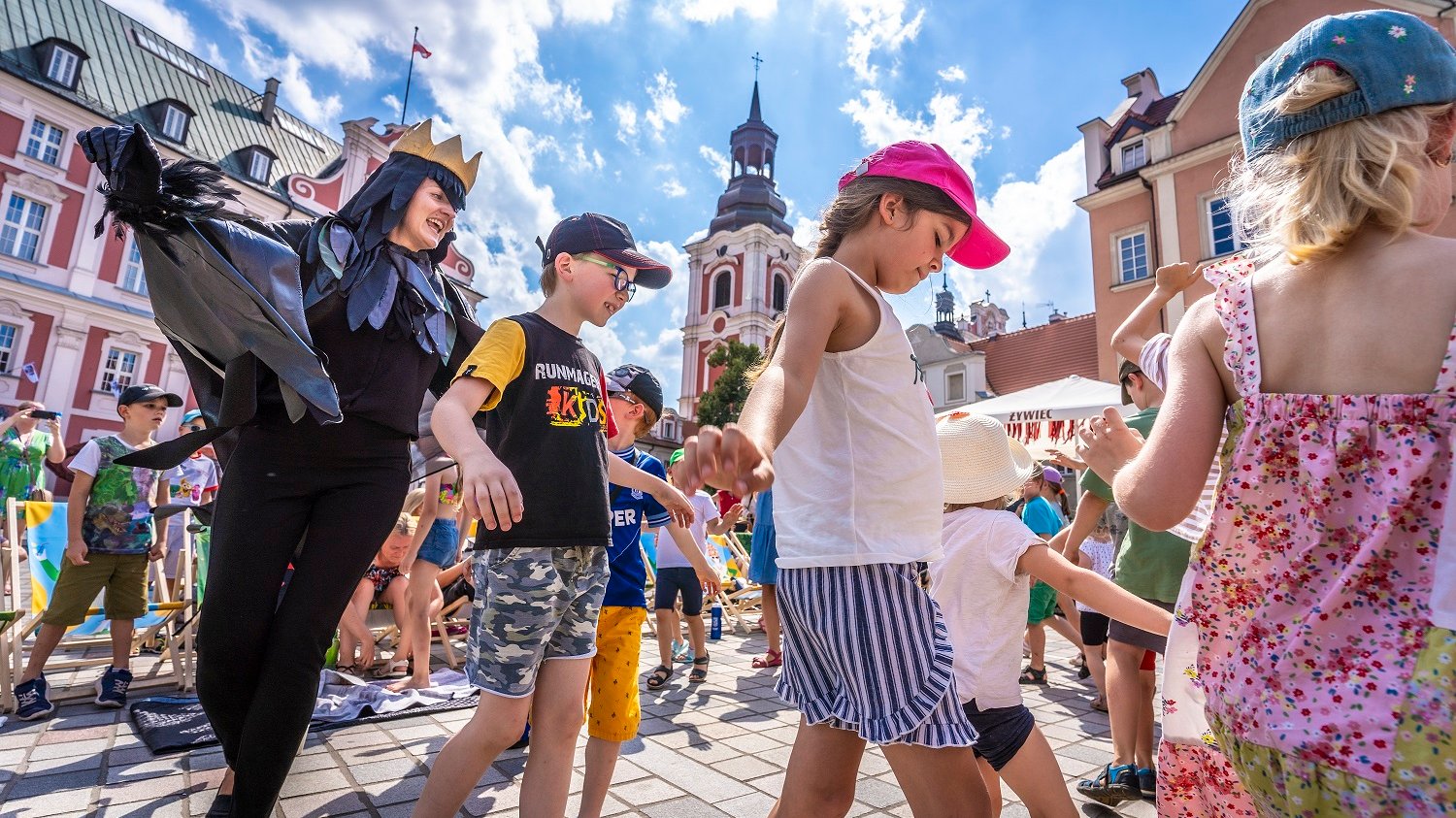 Grupa dzieci uczestniczących w animacjach na placu kolegiackim.