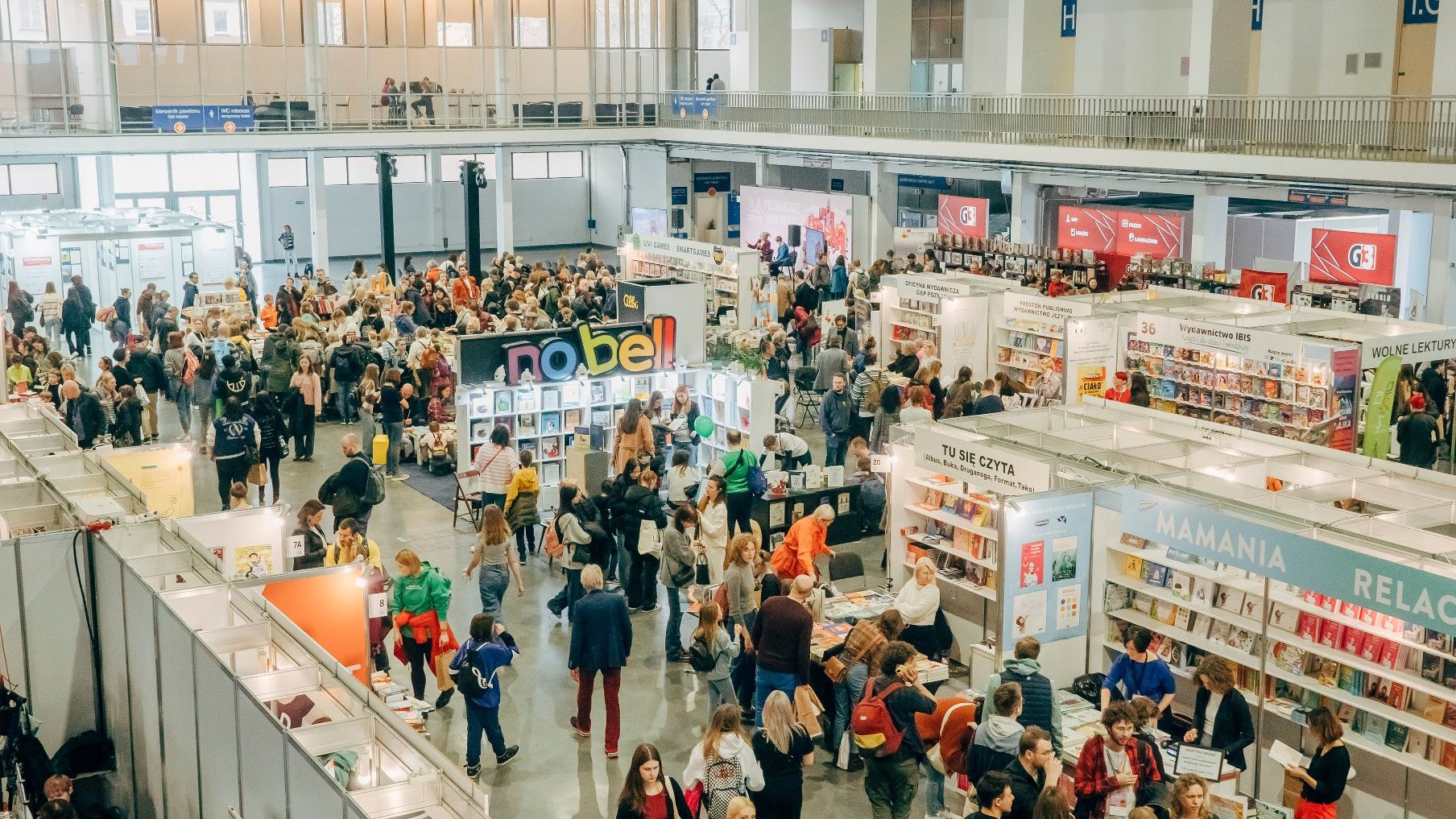 Tłum ludzi spacerujących na targach książki.