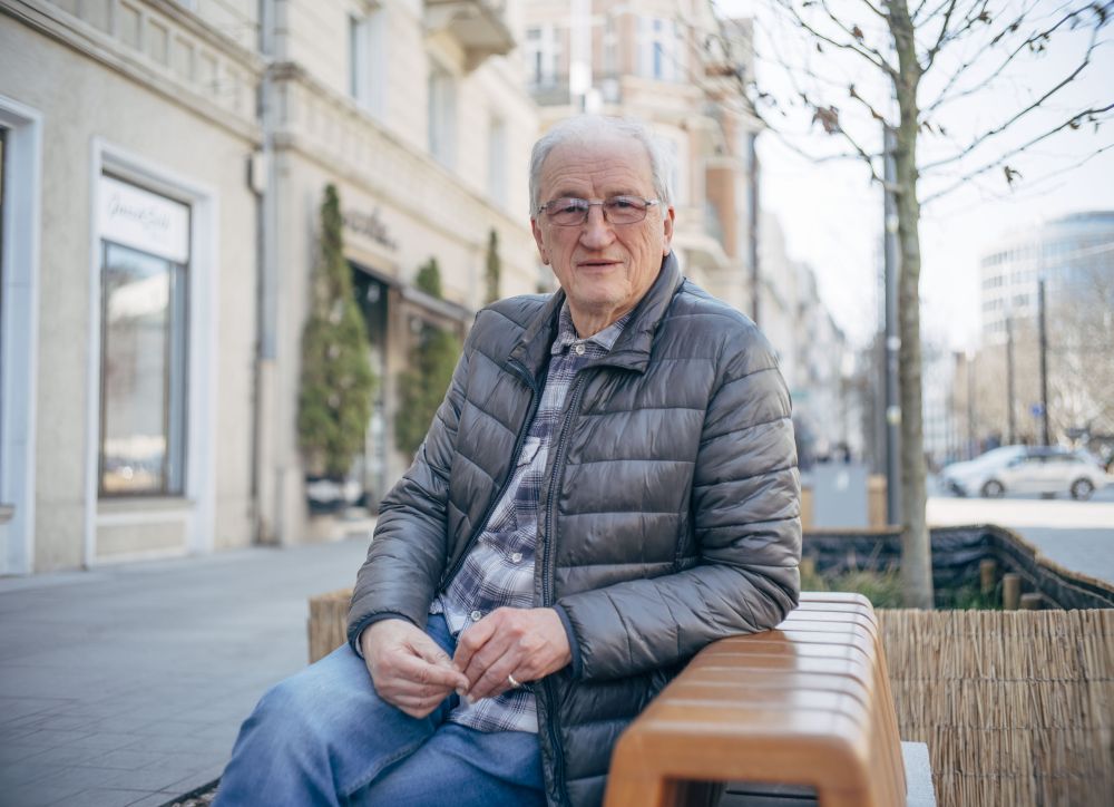 Mężczyzna w niebieskiej pikowanej kurtce siedzi na ławce na ulicy Święty Marcin w Poznaniu. - grafika artykułu