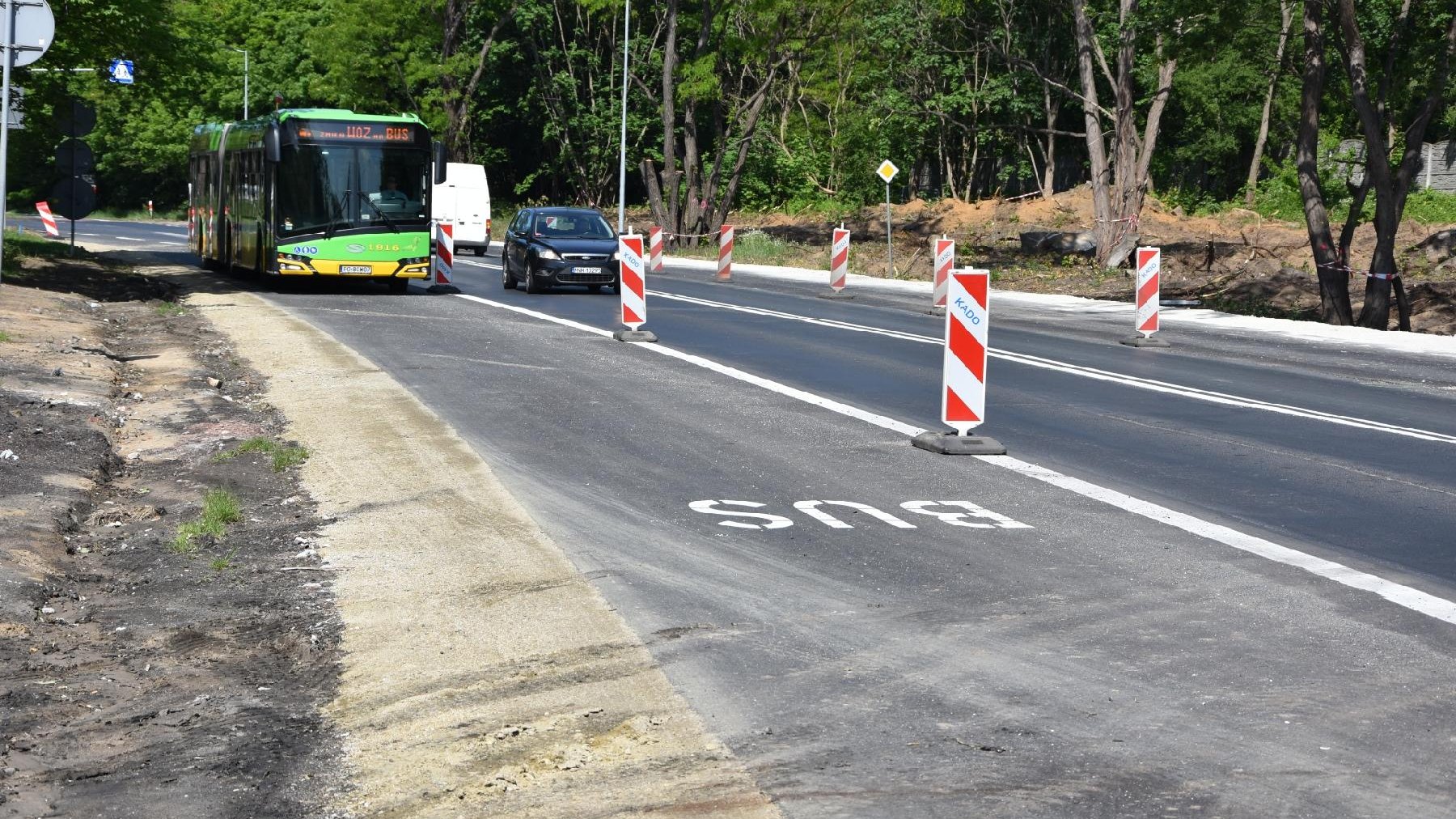 Zdjęcie przedstawia buspas na Winogradach. Po jezdni jedzie autobus i samochód