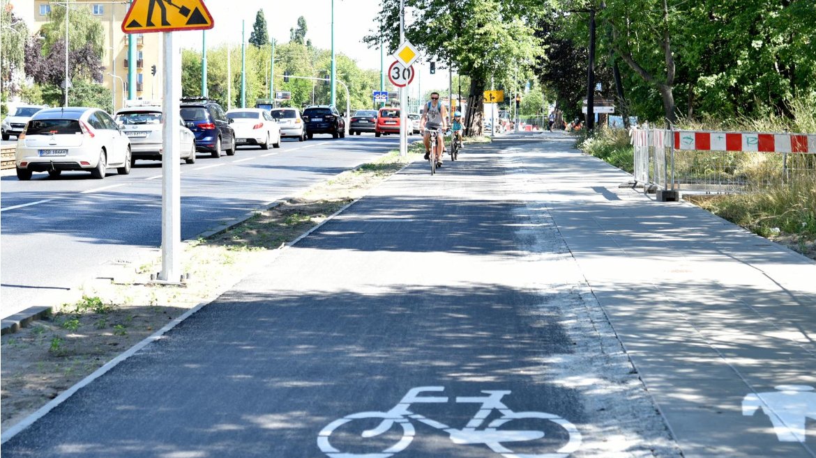 Zdjęcie przedstawia powstającą drogę rowerową na ul. Grunwaldzkiej. Widać na nim rowerzystów oraz samochody